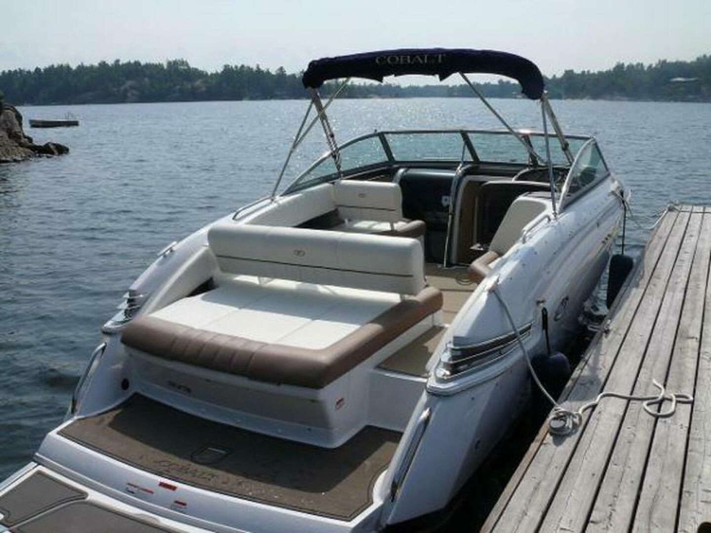 2012 Cobalt 273 boat docked on a serene lake, featuring spacious seating and sleek design.