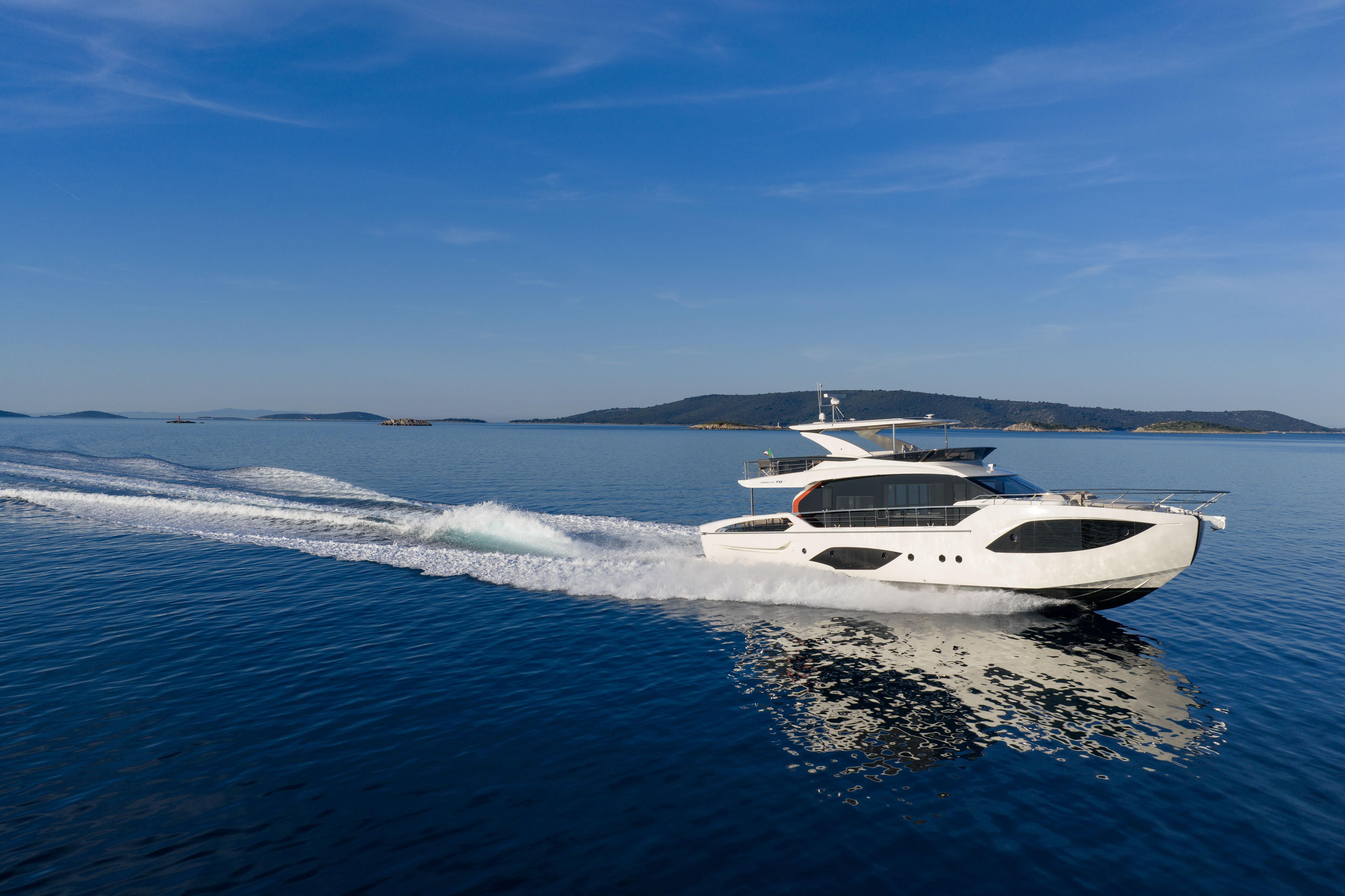 Luxury yacht on calm water with clear skies and distant islands.