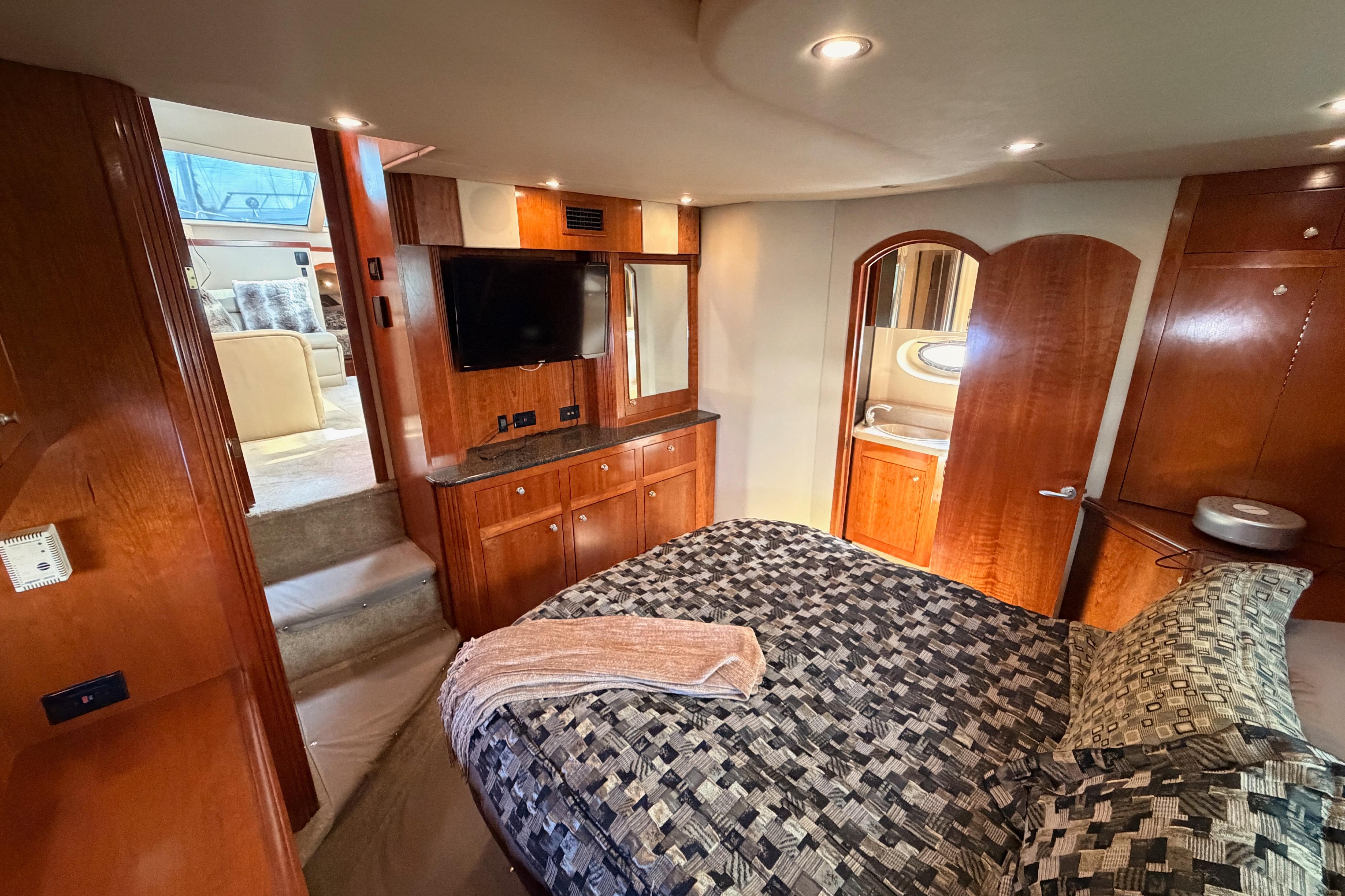 Luxurious 2005 Cruisers Yachts 405 Express Motoryacht bedroom with elegant wood finishes.