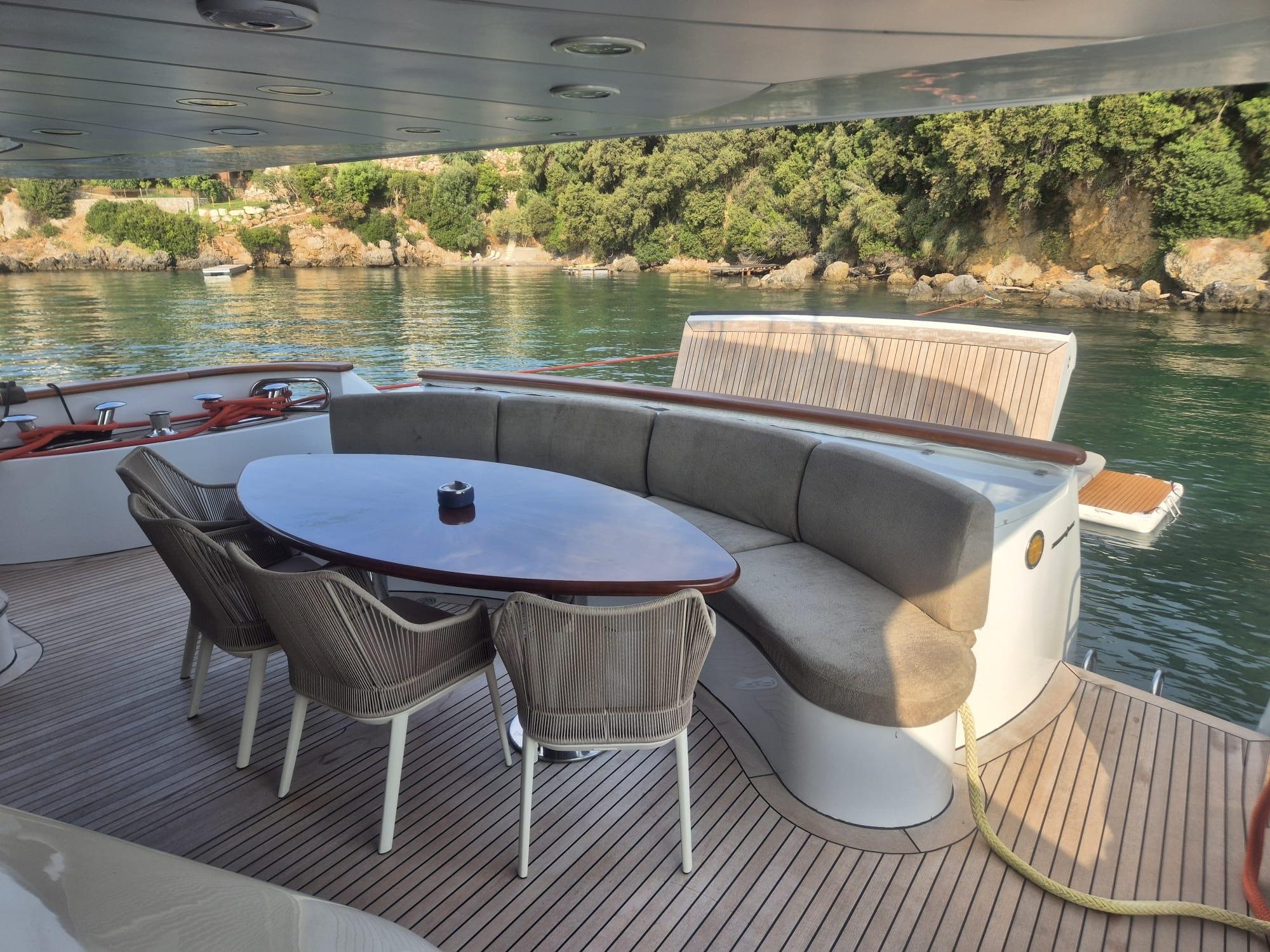 Luxury yacht deck with seating area, Benetti Classic 115, 2000 model, near scenic shoreline.