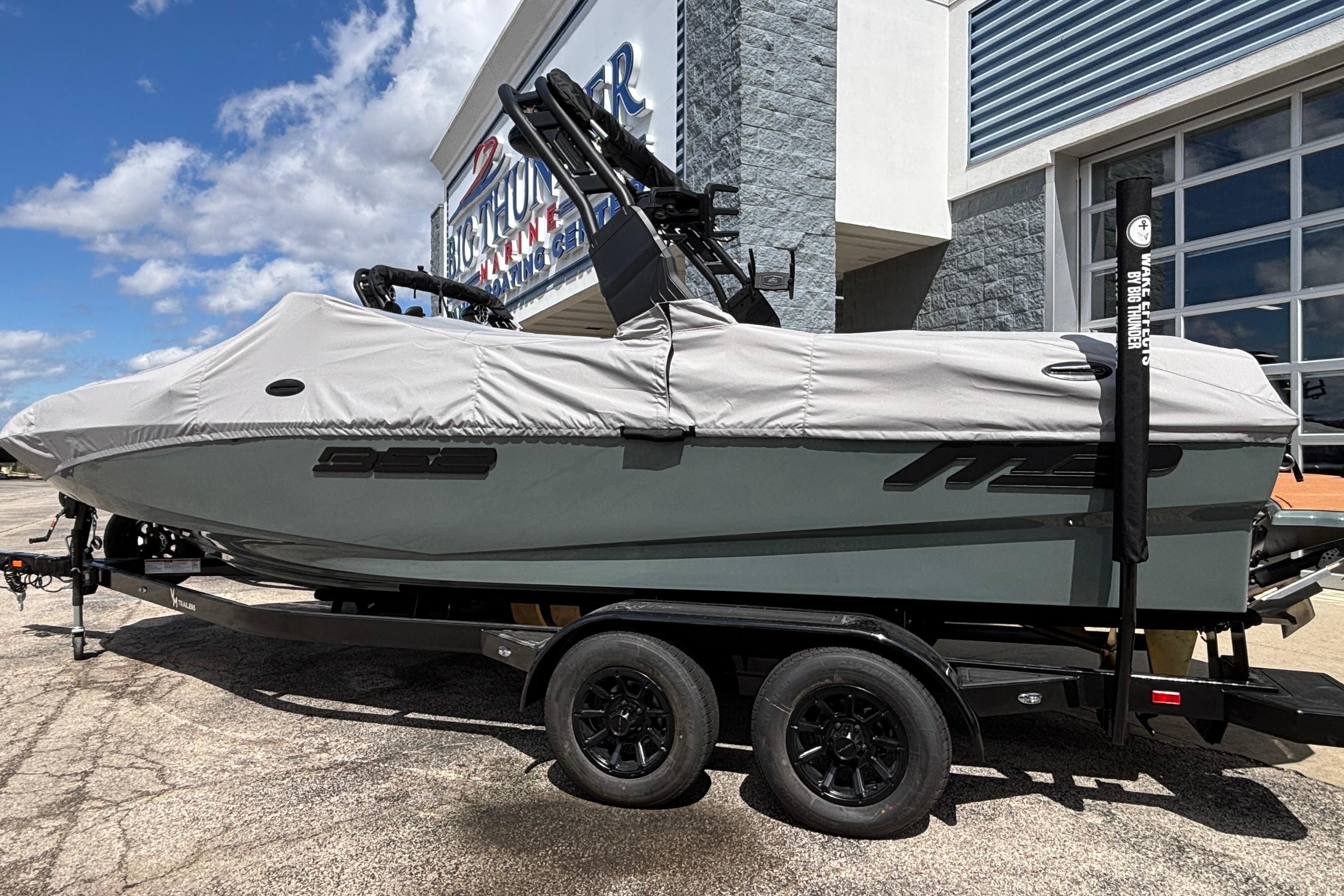 2026 MB B52 23 Classic boat on trailer, covered, outside dealership under blue sky.