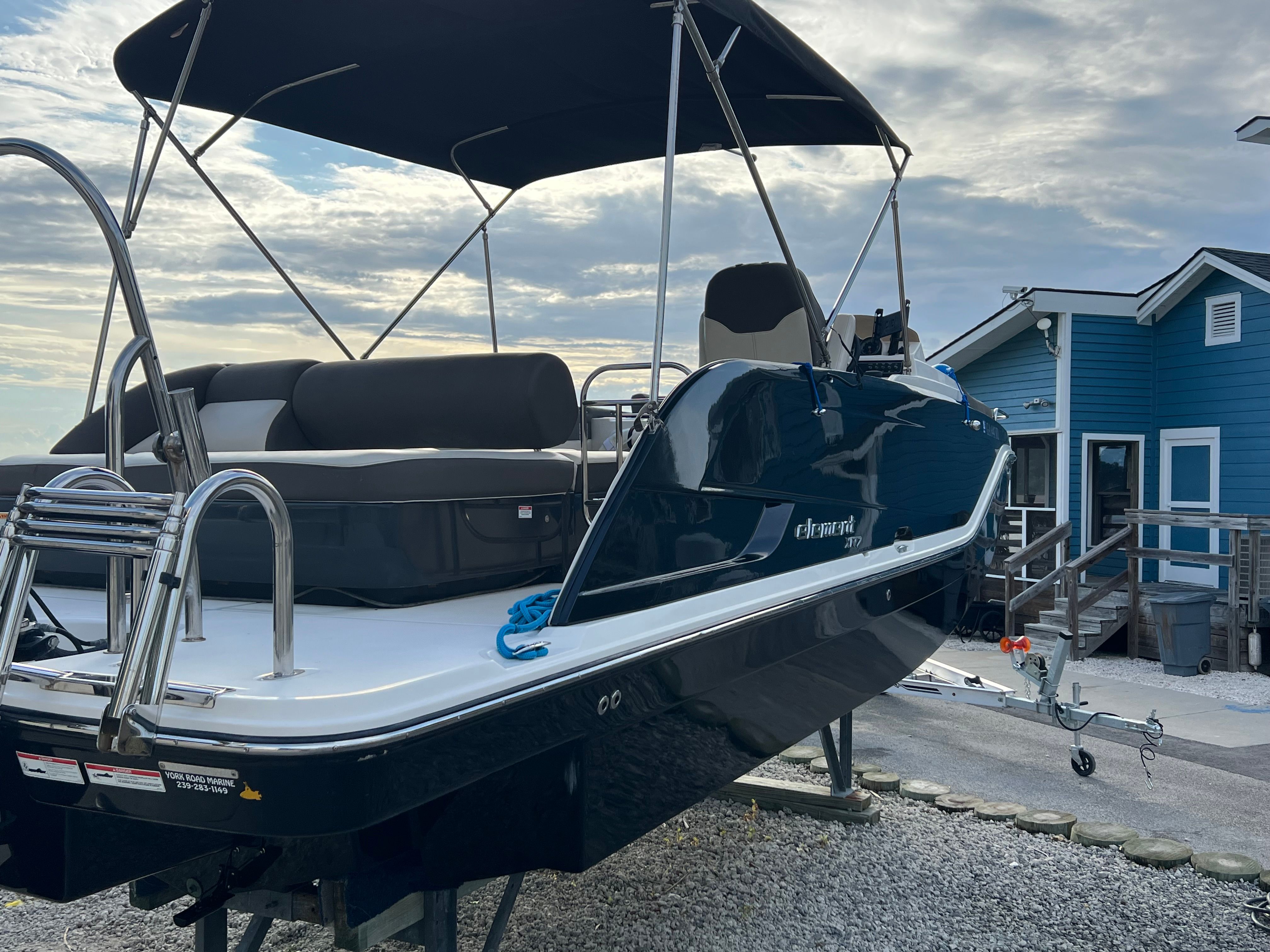 A 2019 Bayliner Element XR7 on a trailer in front of a blue building.