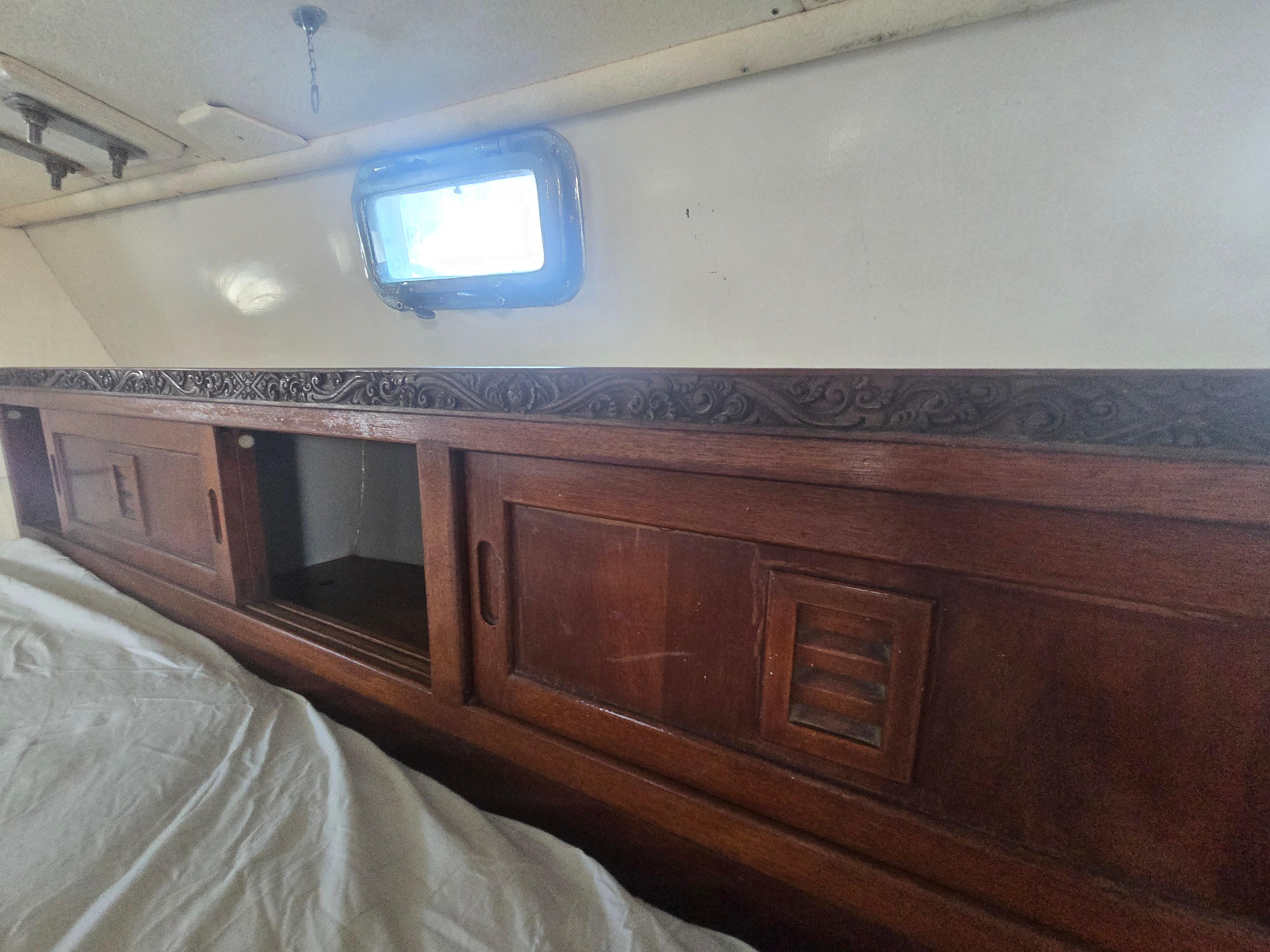 1978 Herreshoff 50 interior with wooden cabinets and porthole window.