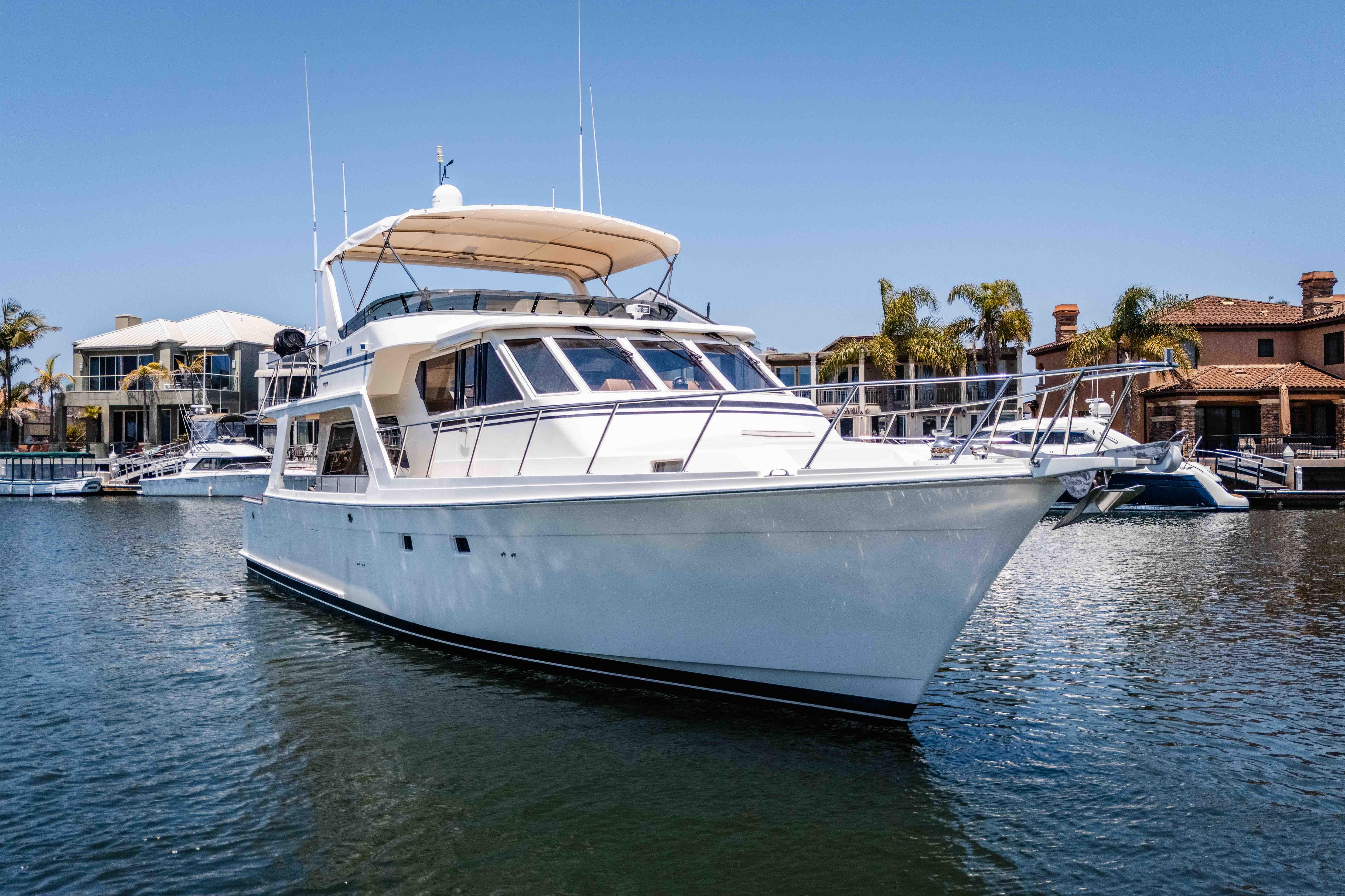 2005 Offshore Yachts 54 Pilothouse in marina, surrounded by waterfront homes and palm trees.