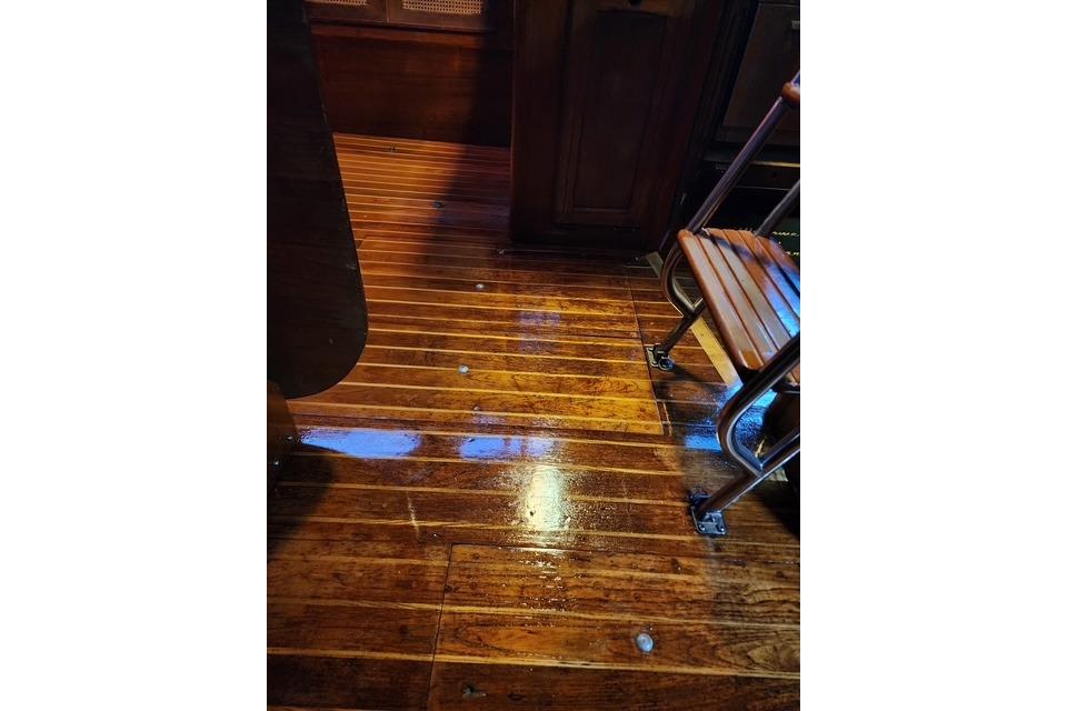 Polished wooden floor inside 1984 Bristol 45.5 Center Cockpit yacht, featuring a metal-framed chair.