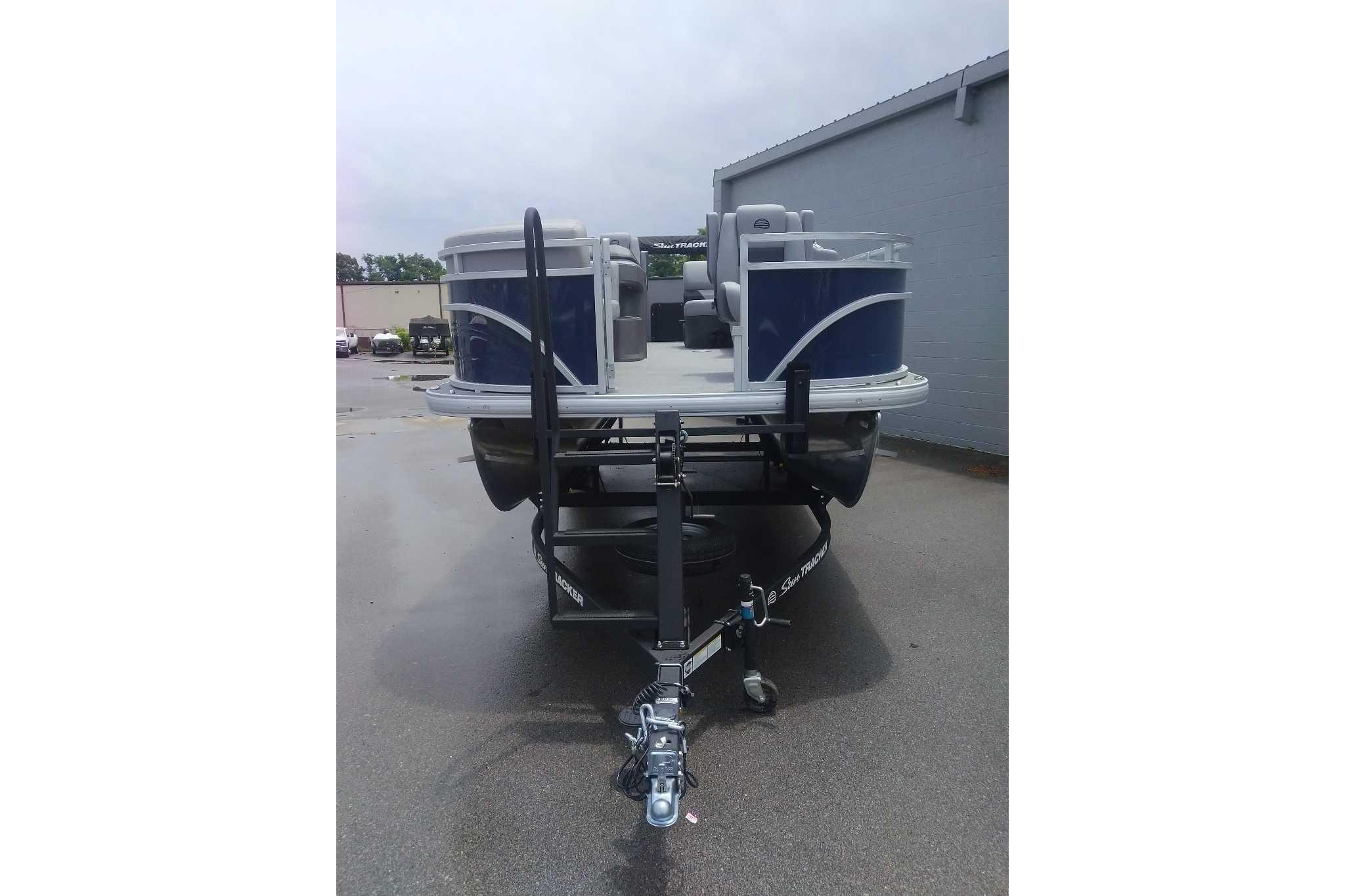 2026 Sun Tracker SportFish 20 DLX pontoon boat on trailer, parked outdoors.