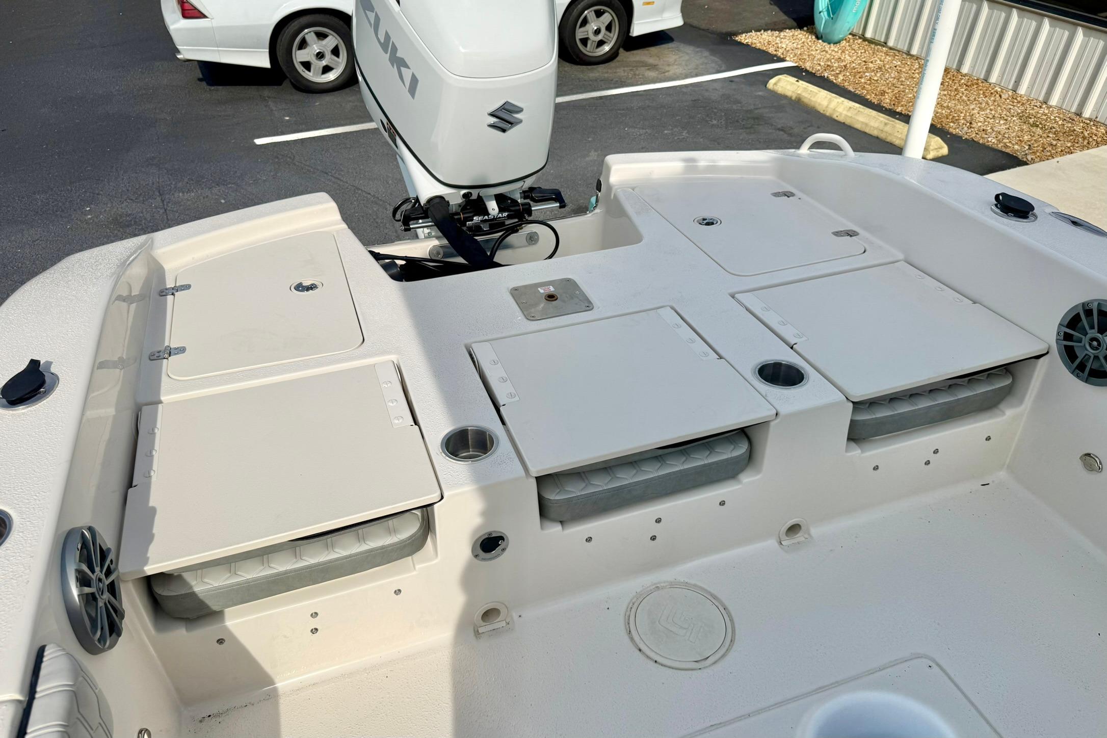 2026 Carolina Skiff 24 Ultra Elite boat deck with Suzuki motor, storage compartments, and cup holders.