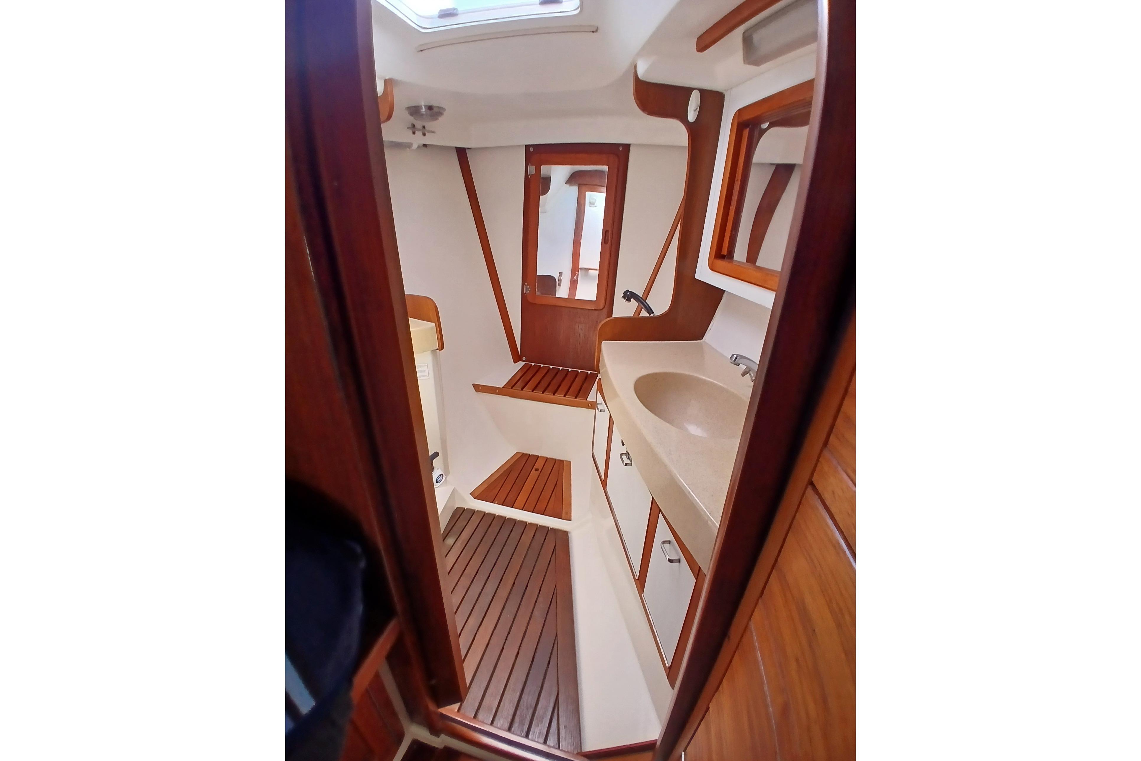 Interior of 1995 Catalina 42 MkII sailboat, featuring wooden cabinetry and compact bathroom.