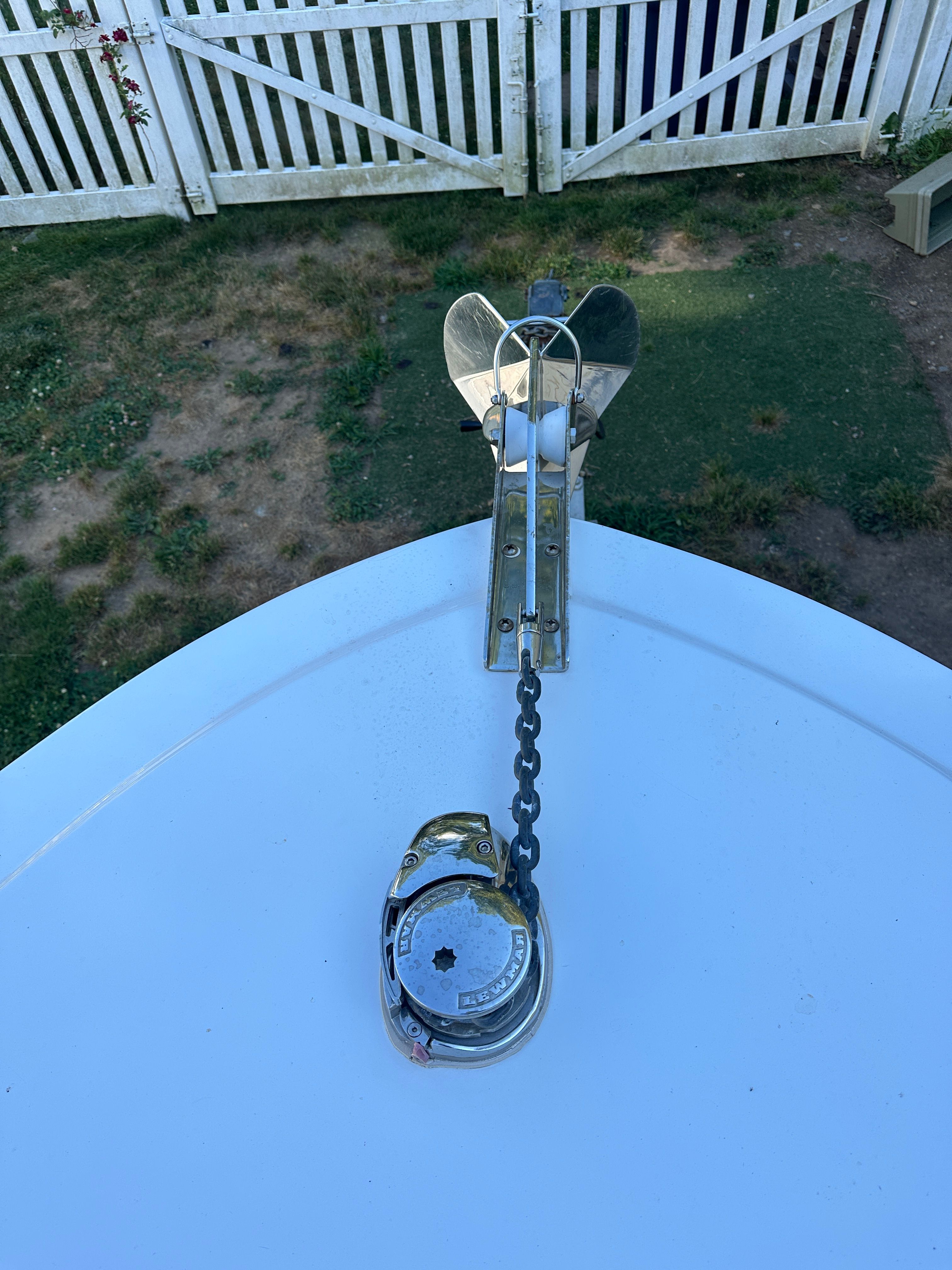 An anchor is attached to the front of a boat, which is on a lawn.