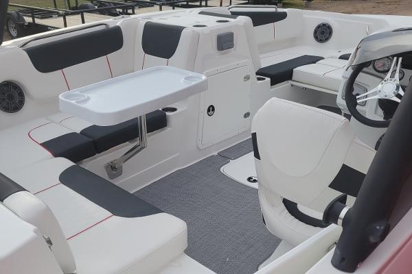 2024 Tahoe 1950 boat interior with white and black seating, table, and steering wheel.