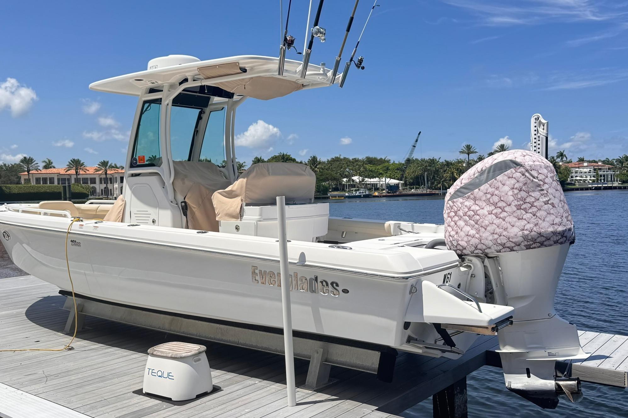 2018 Everglades 253 Center Console boat docked by waterfront homes under blue sky.