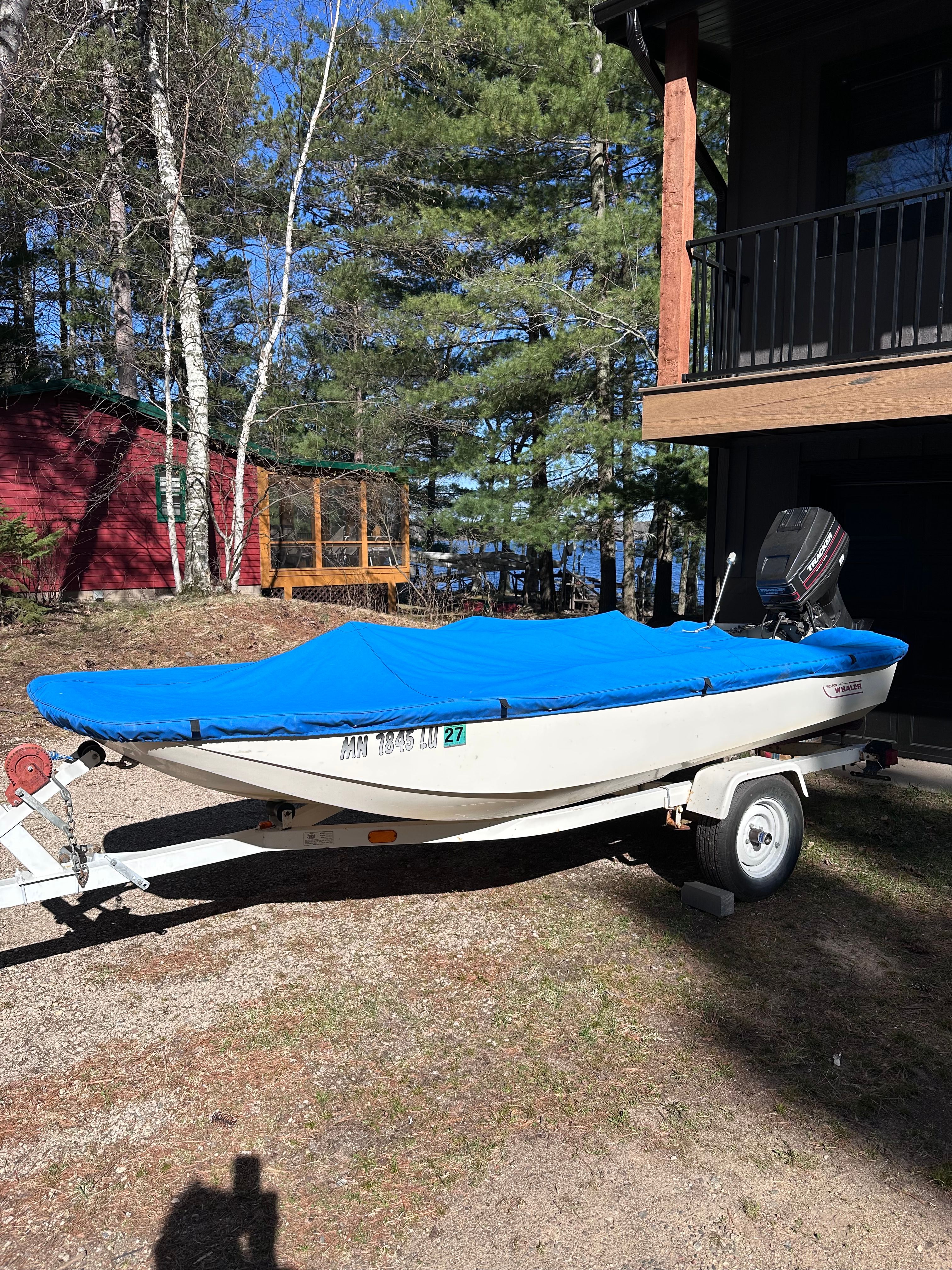 1973 Boston Whaler Sourpuss boat with blue cover on trailer.