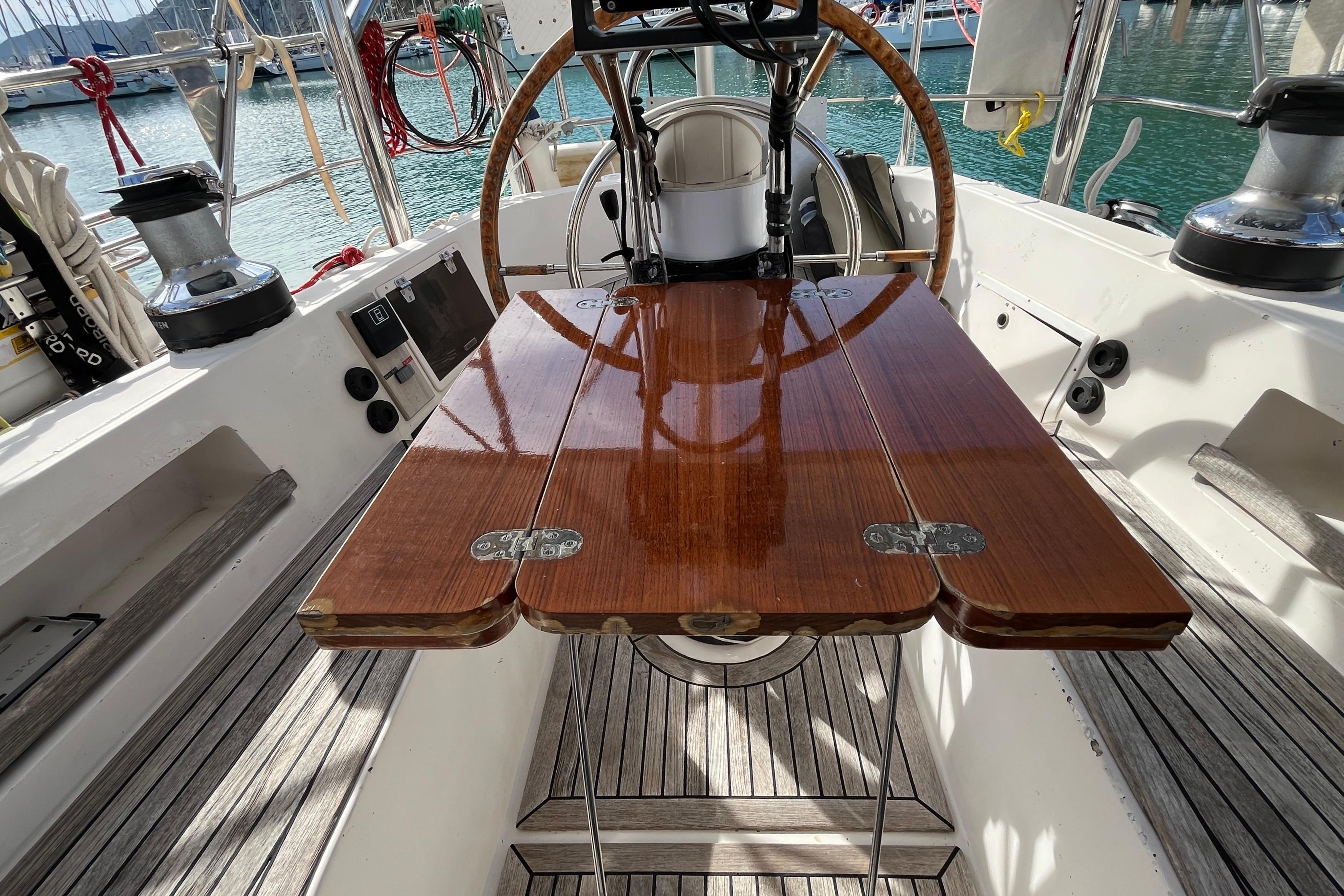 Cockpit of 1995 Belliure 41 yacht with polished wooden table and steering wheel.