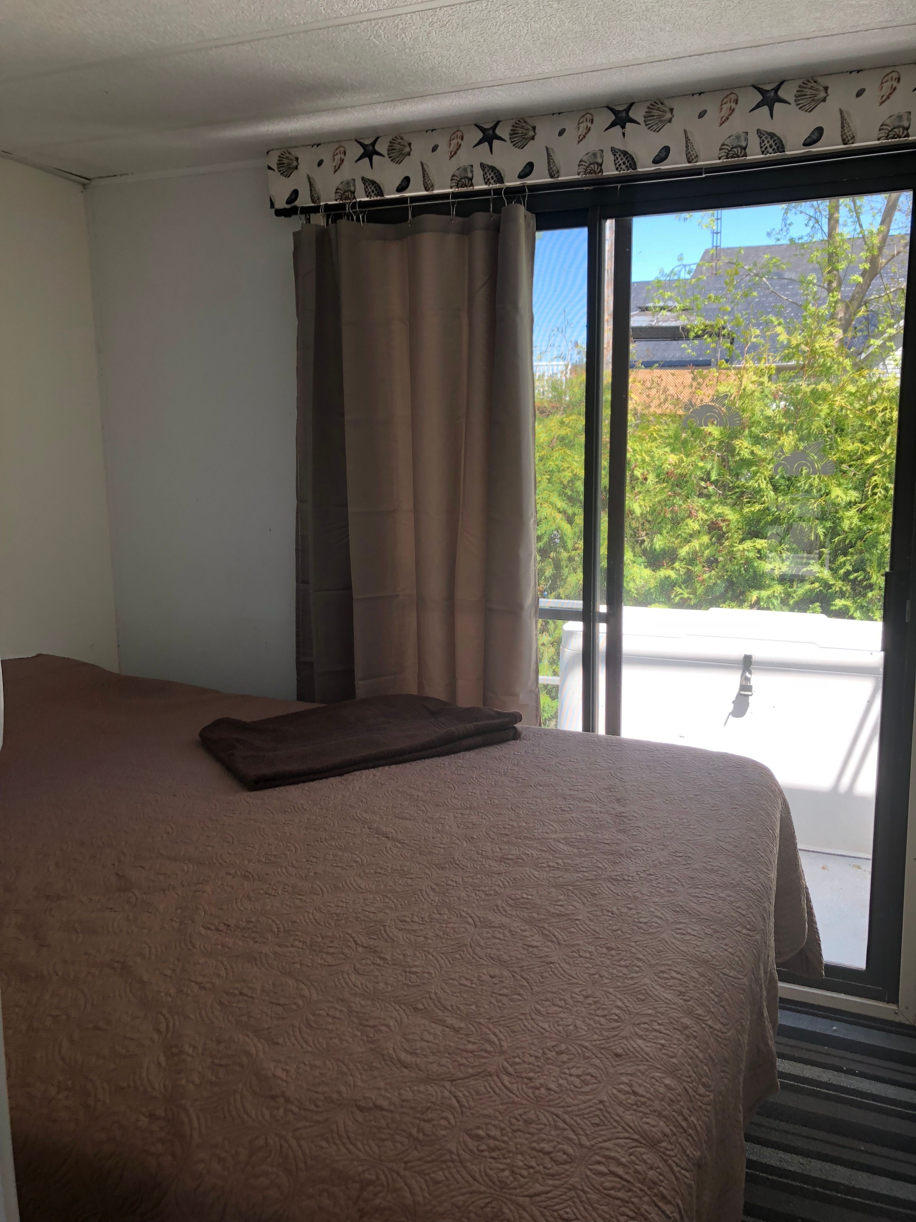 A cozy bedroom with a large bed and a window overlooking greenery.