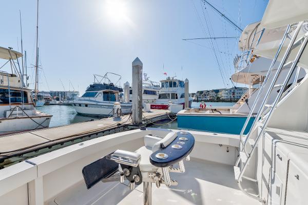 1999 Viking 47 Convertible yacht docked at marina under bright sunlight.