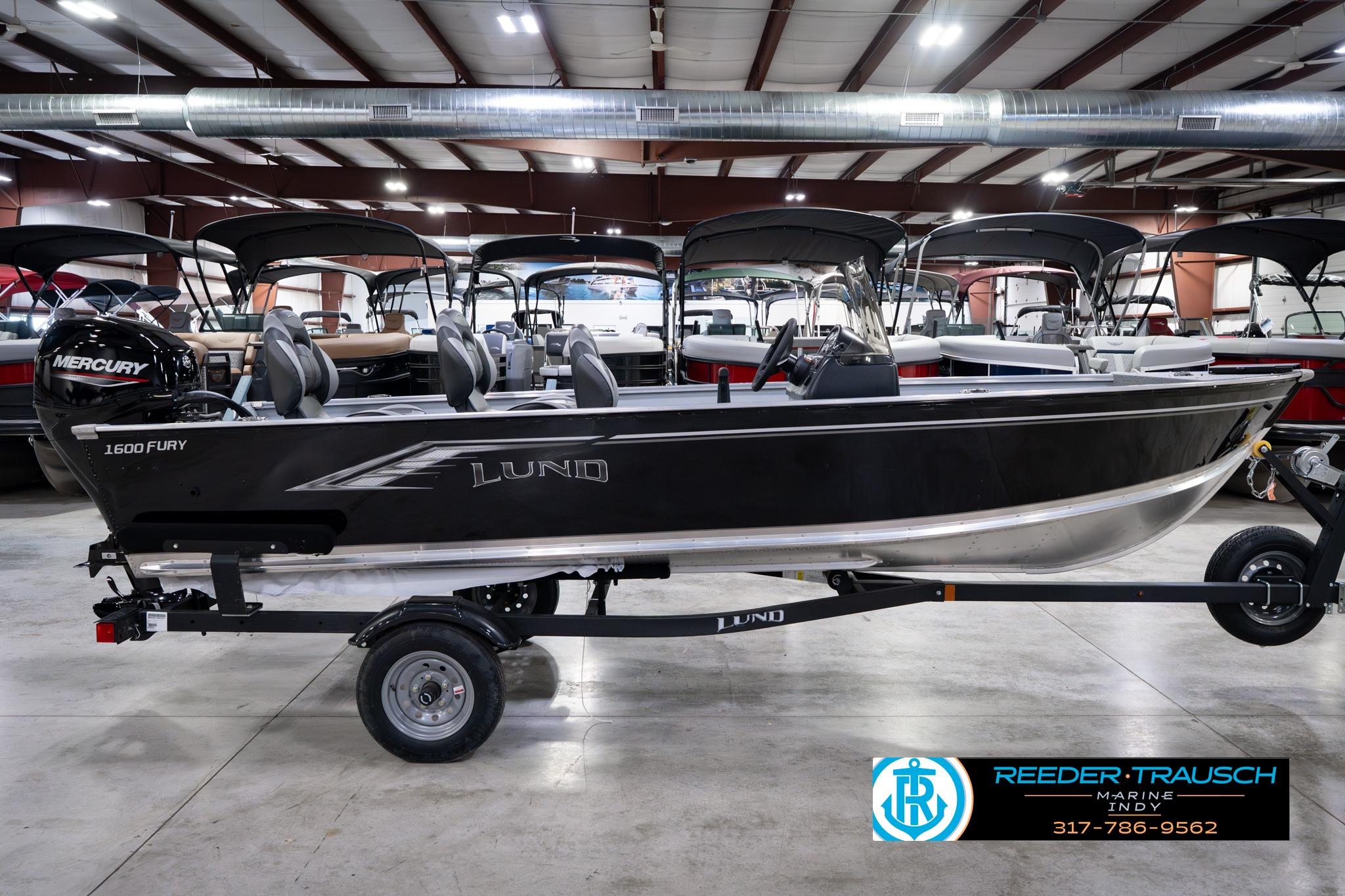 2026 Lund 1600 Fury SS boat in showroom, featuring sleek black design and Mercury engine.