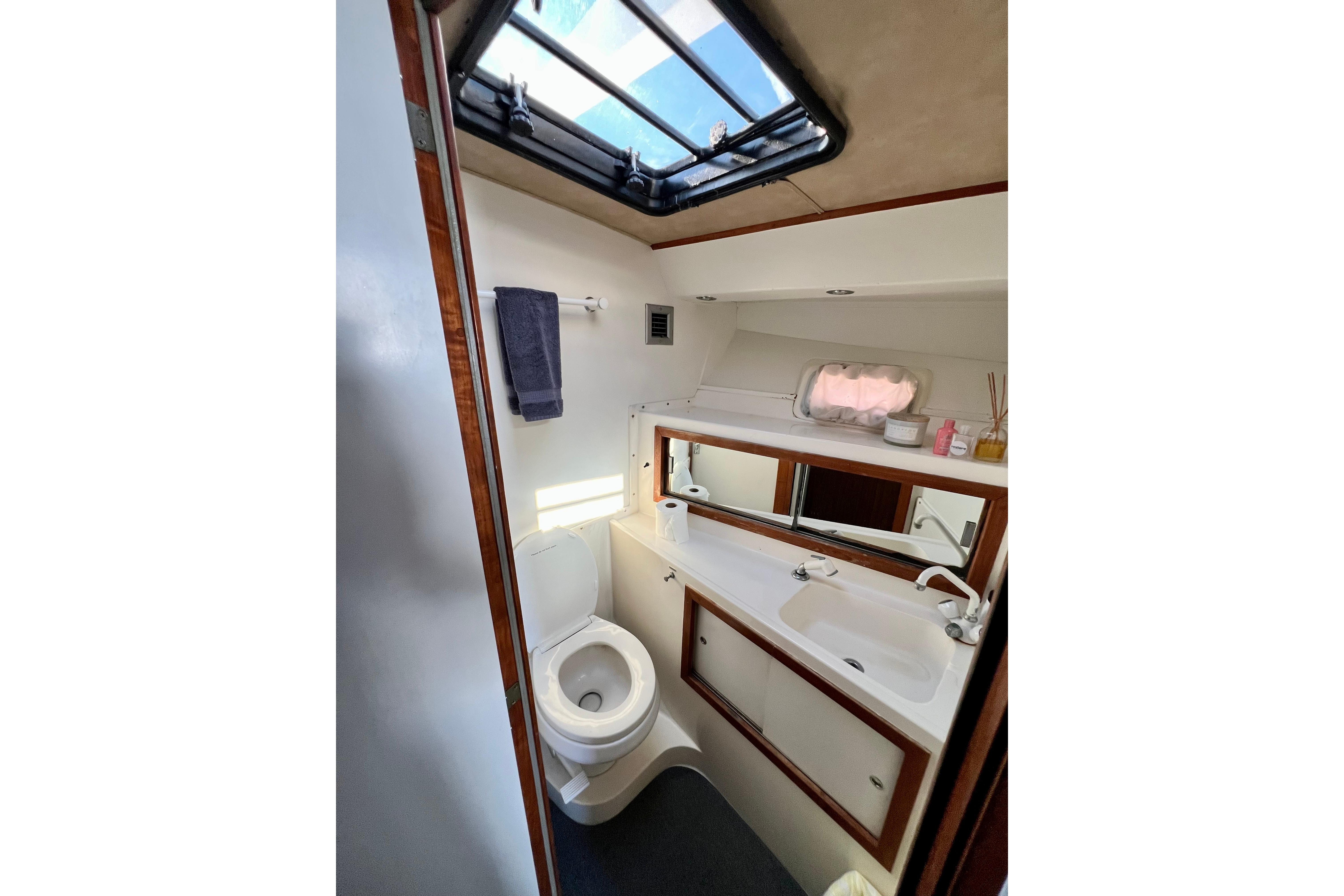 1982 Bertram 46 Convertible yacht bathroom with skylight, toilet, and sink.