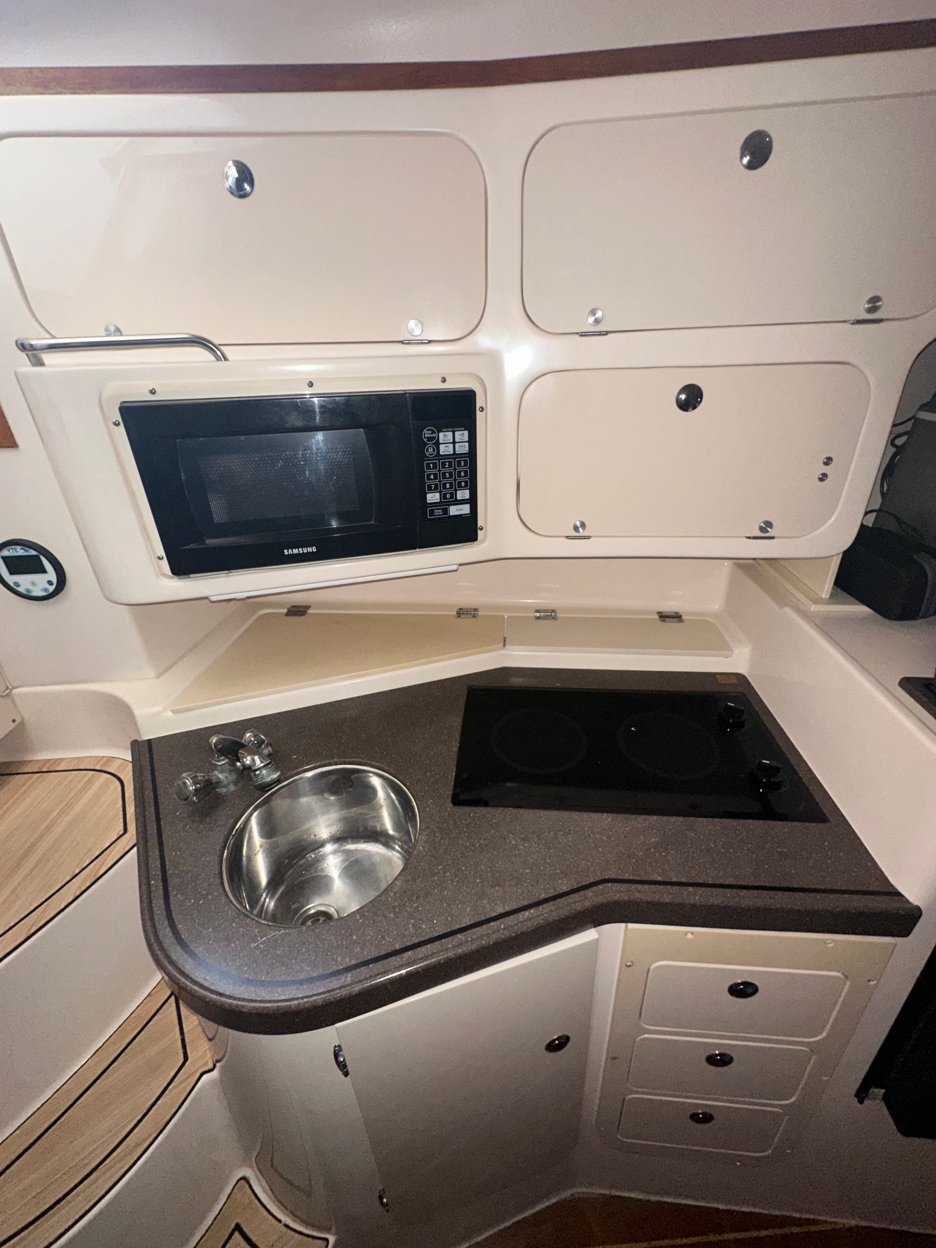 Galley area with sink, microwave, and stove in a boat.