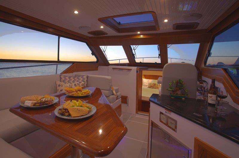 Luxurious 2024 True North 34 yacht interior with dining area and ocean view.