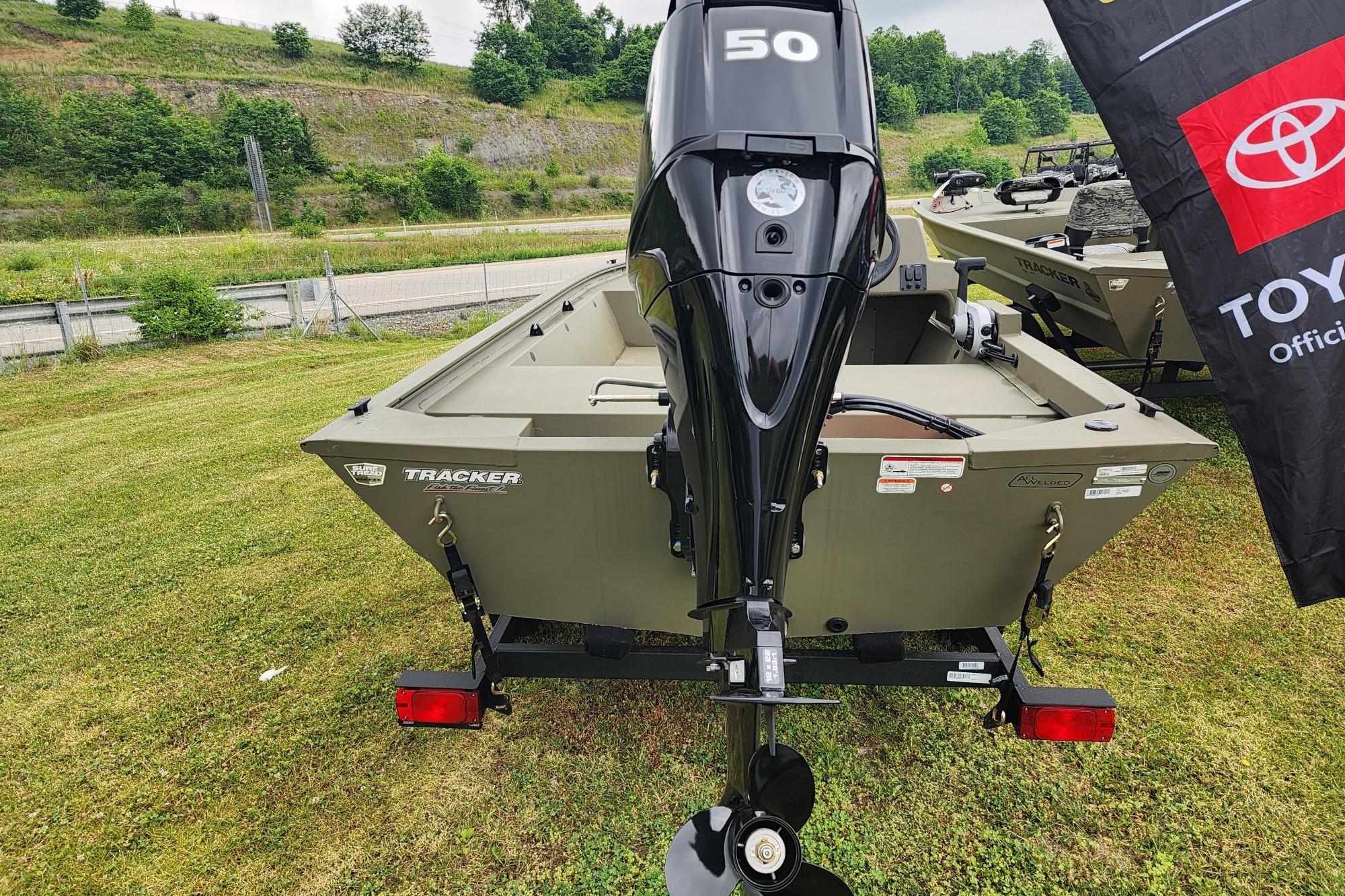 2026 Tracker Grizzly 1648 SC boat with 50 HP motor on grassy landscape.