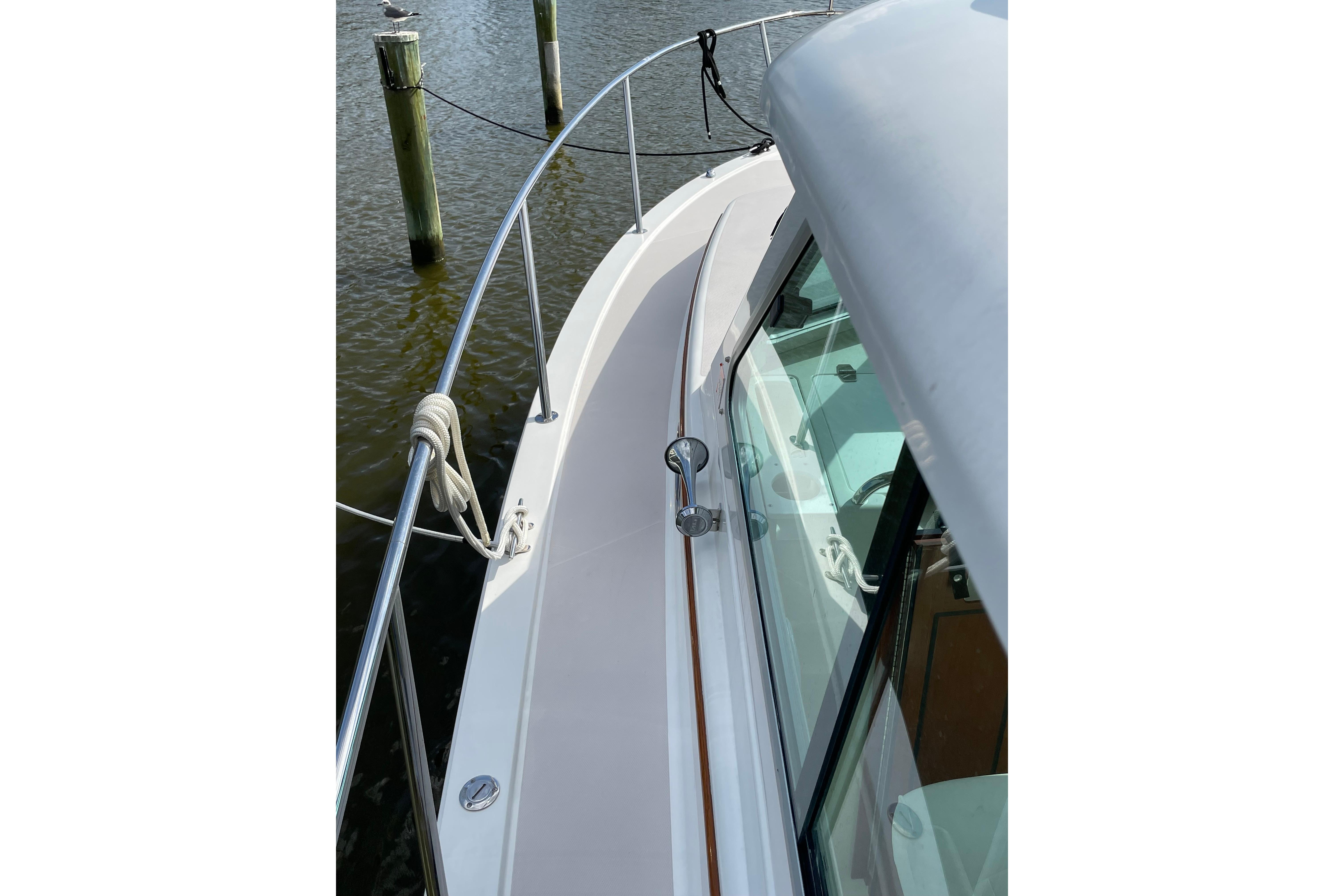 2007 Back Cove 29 boat deck with railing, docked by wooden posts.