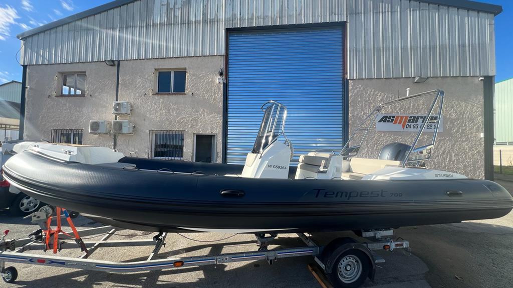 2023 Capelli Tempest 700 boat on trailer, parked outside industrial building.