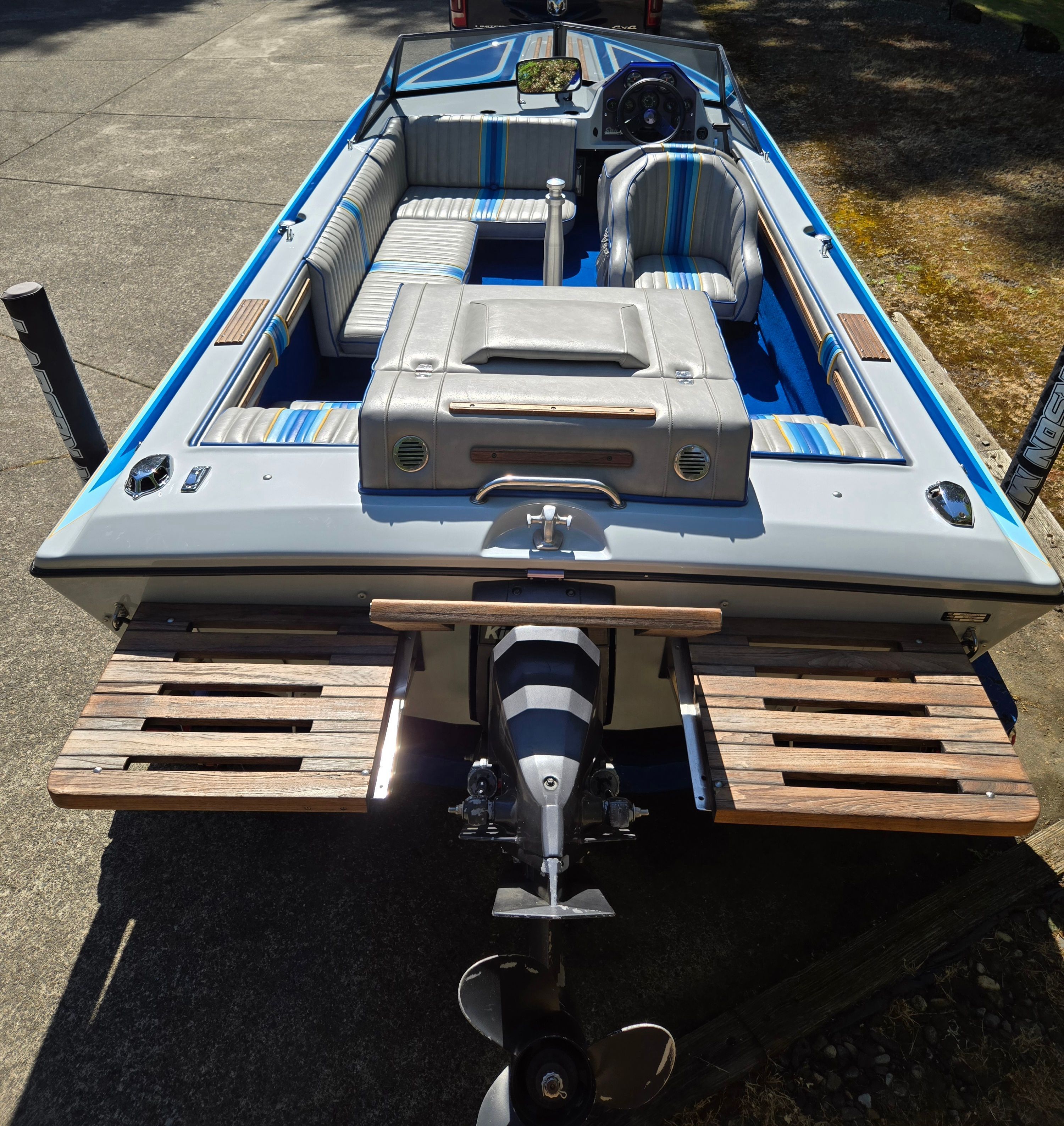 A 1990 Sanger Ski Sanger boat with striped seats and an outboard motor.