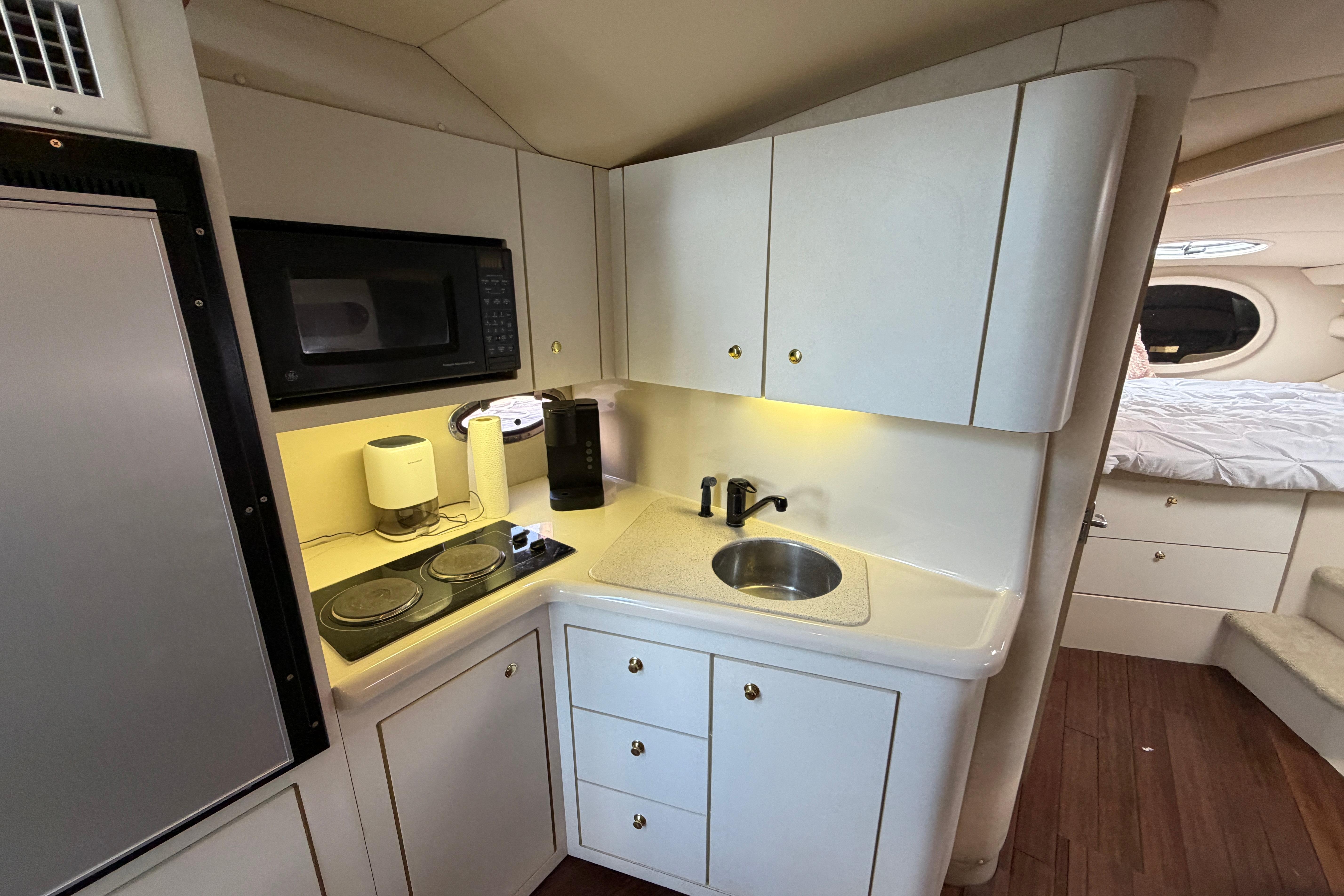1997 Cruisers 3575 yacht kitchen with microwave, stove, sink, and cabinetry.