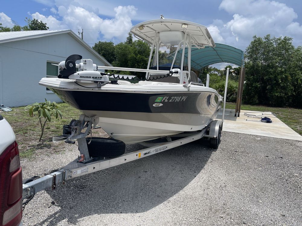 A white boat on a trailer with a covered area in the background.