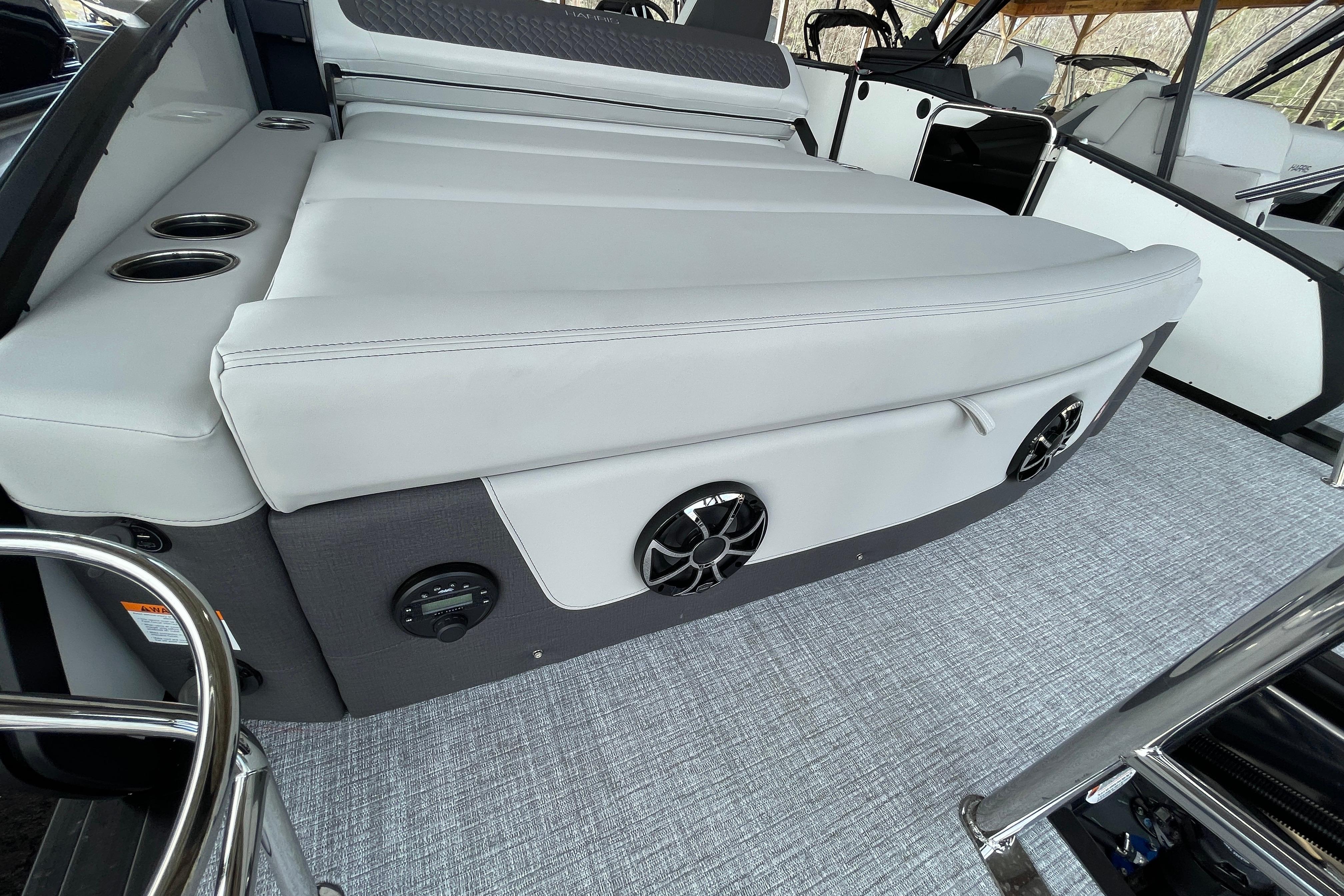 2026 Harris Sunliner 230 boat interior with cushioned seating and built-in speakers.