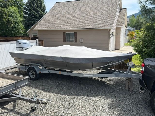 2008 Willie Boats Predator on trailer, covered, parked beside house.