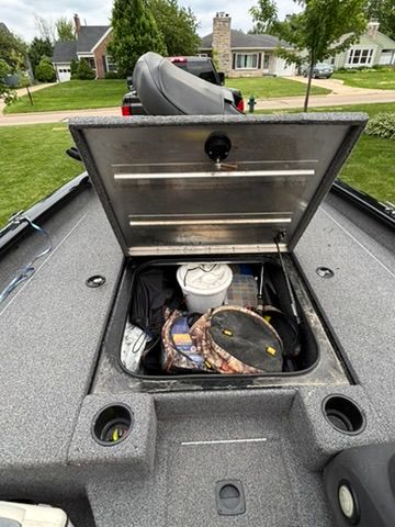 An open storage compartment on a Bass Tracker Pro 175TXW boat, filled with fishing gear.