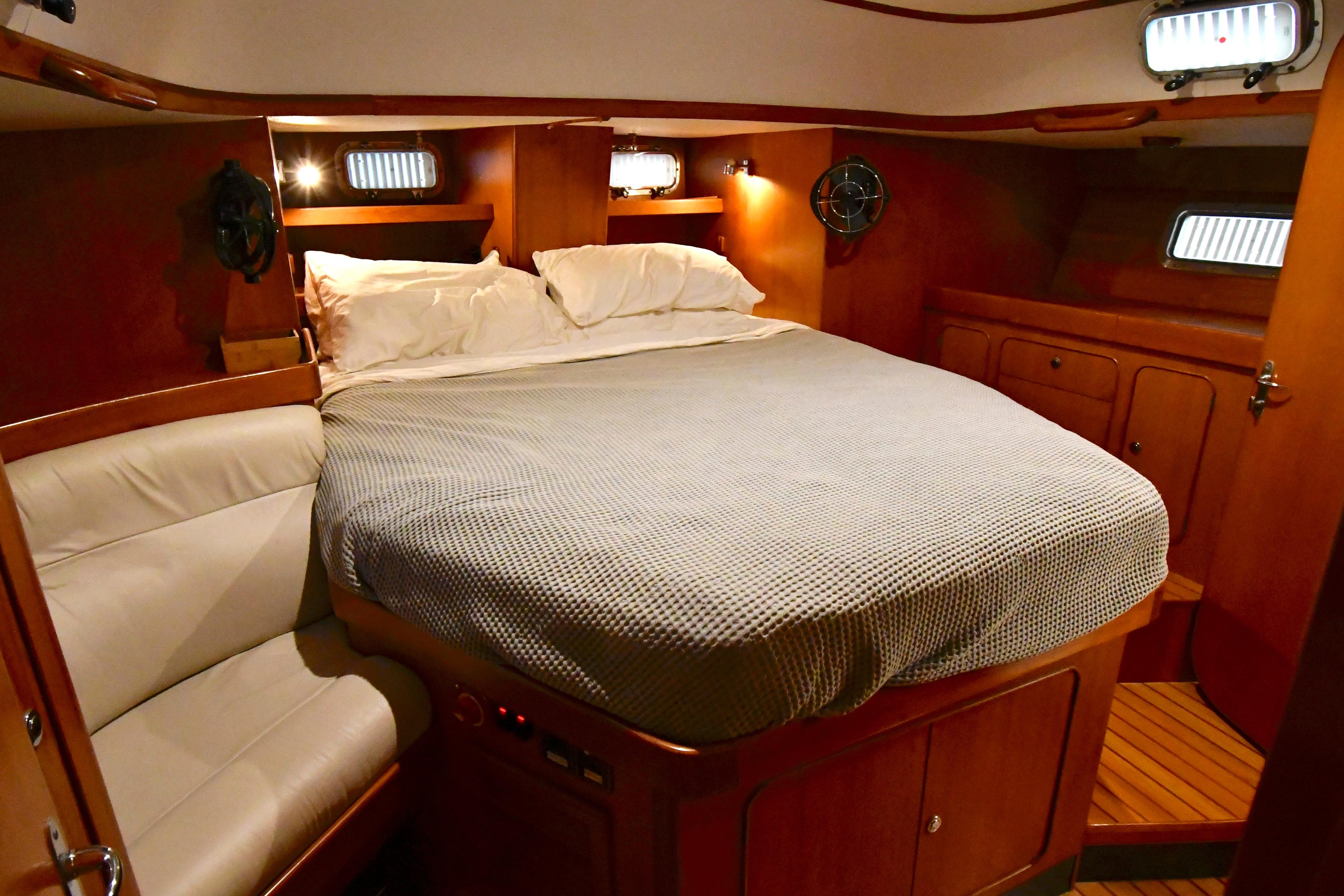 Luxurious cabin interior of a 2002 Hylas 46 yacht with cozy bedding and wooden furnishings.