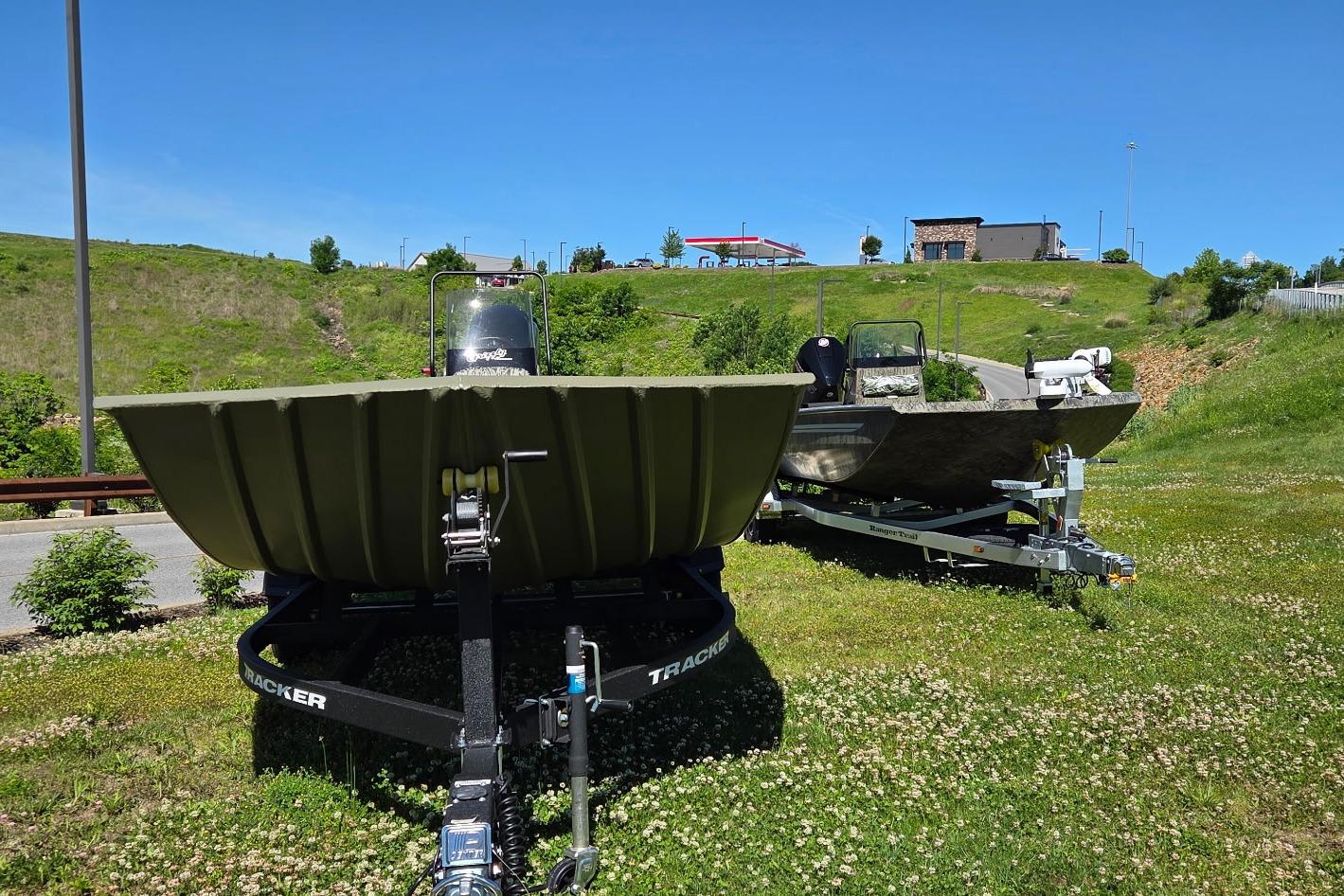2026 Tracker Grizzly 2072 CC boats on trailers in grassy area under clear blue sky.