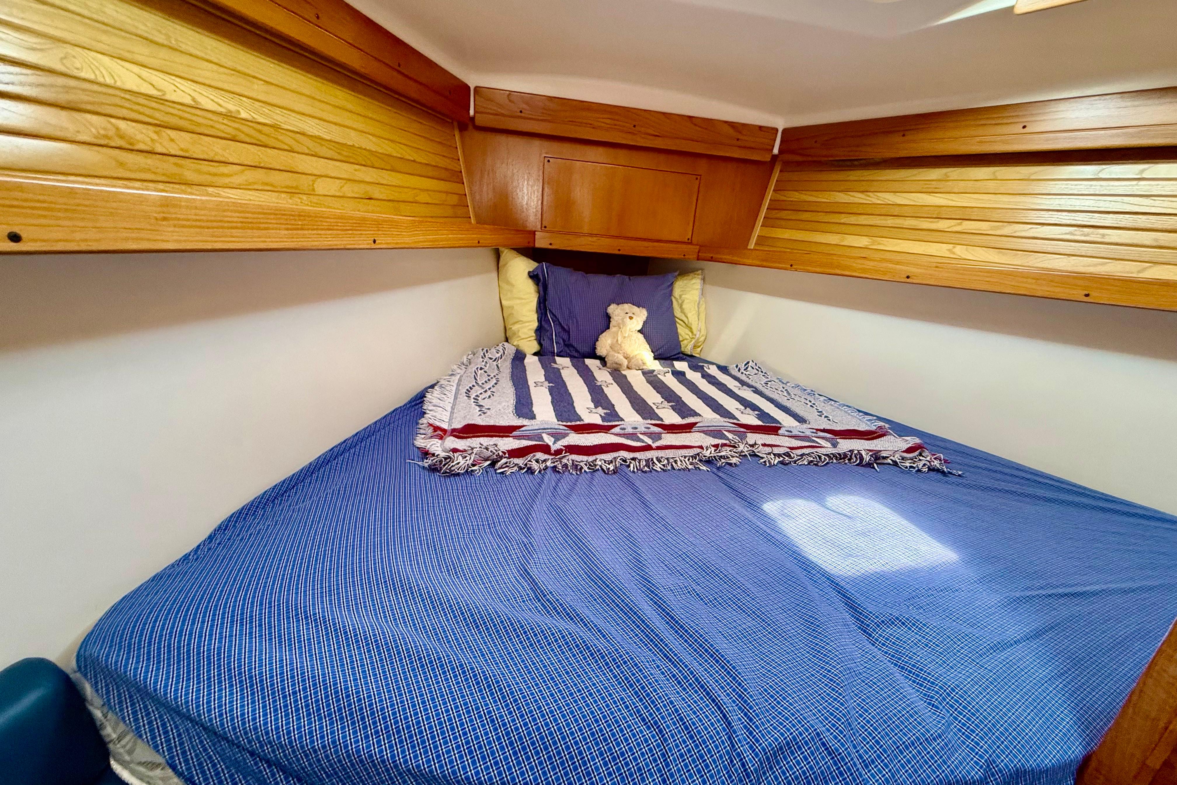 Cozy cabin bed in 2002 Catalina 400 MkII sailboat with wooden accents and plush decor.