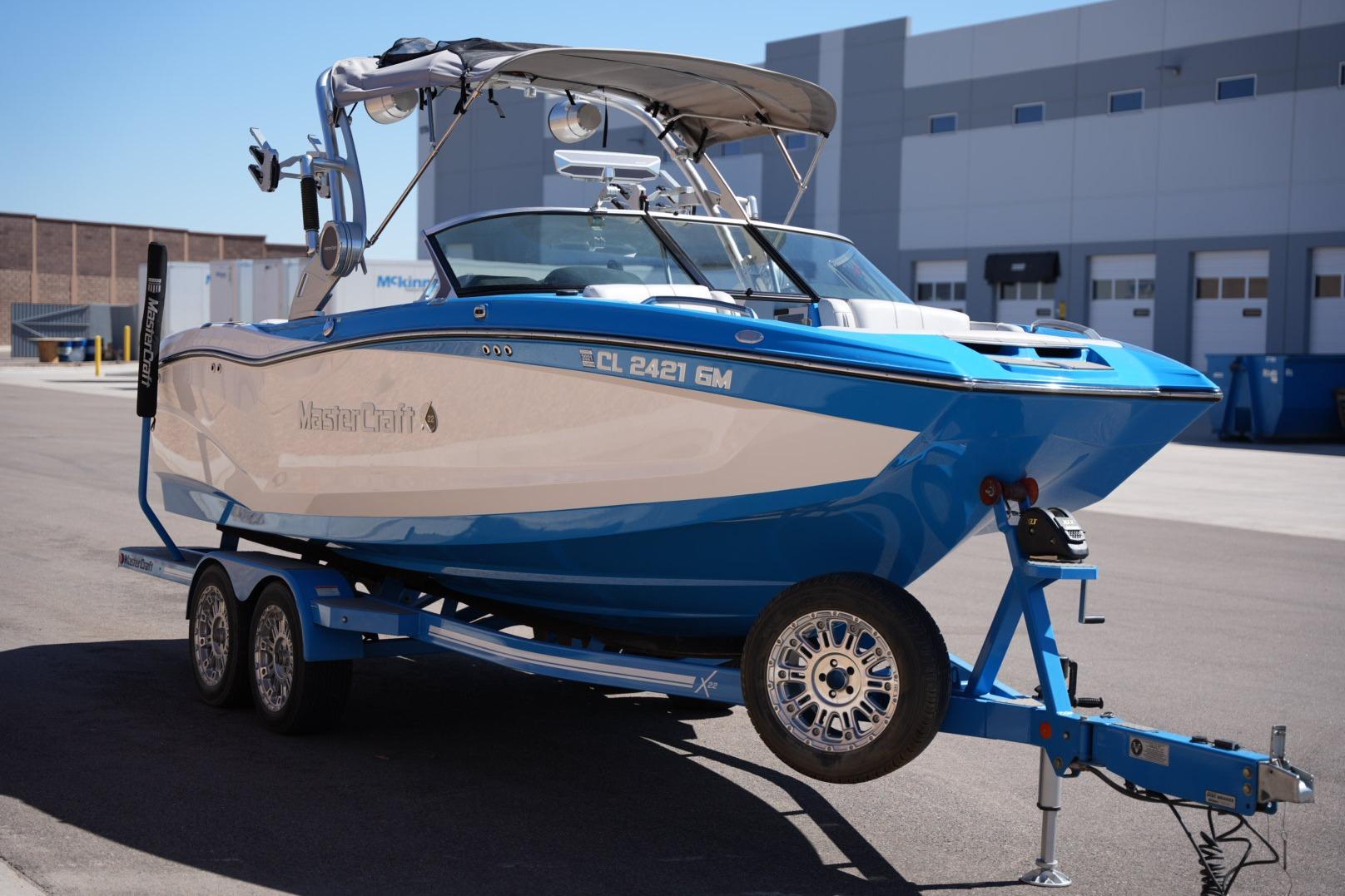 2020 MasterCraft X22 boat on trailer, blue and white, parked outdoors.