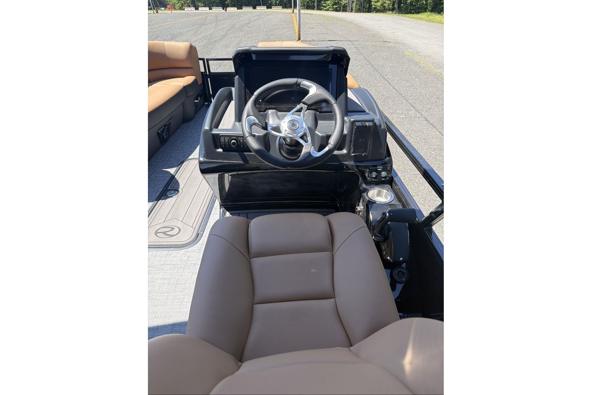2026 Regency 230 DL boat interior with steering wheel and brown seating.