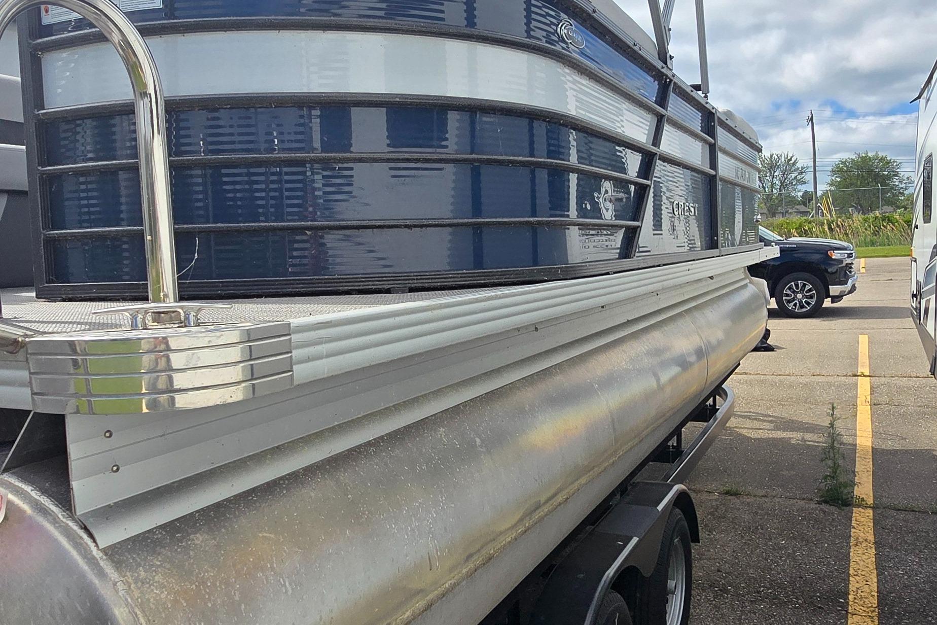 2021 Crest Classic LX 220 SLC pontoon boat on trailer in parking lot.