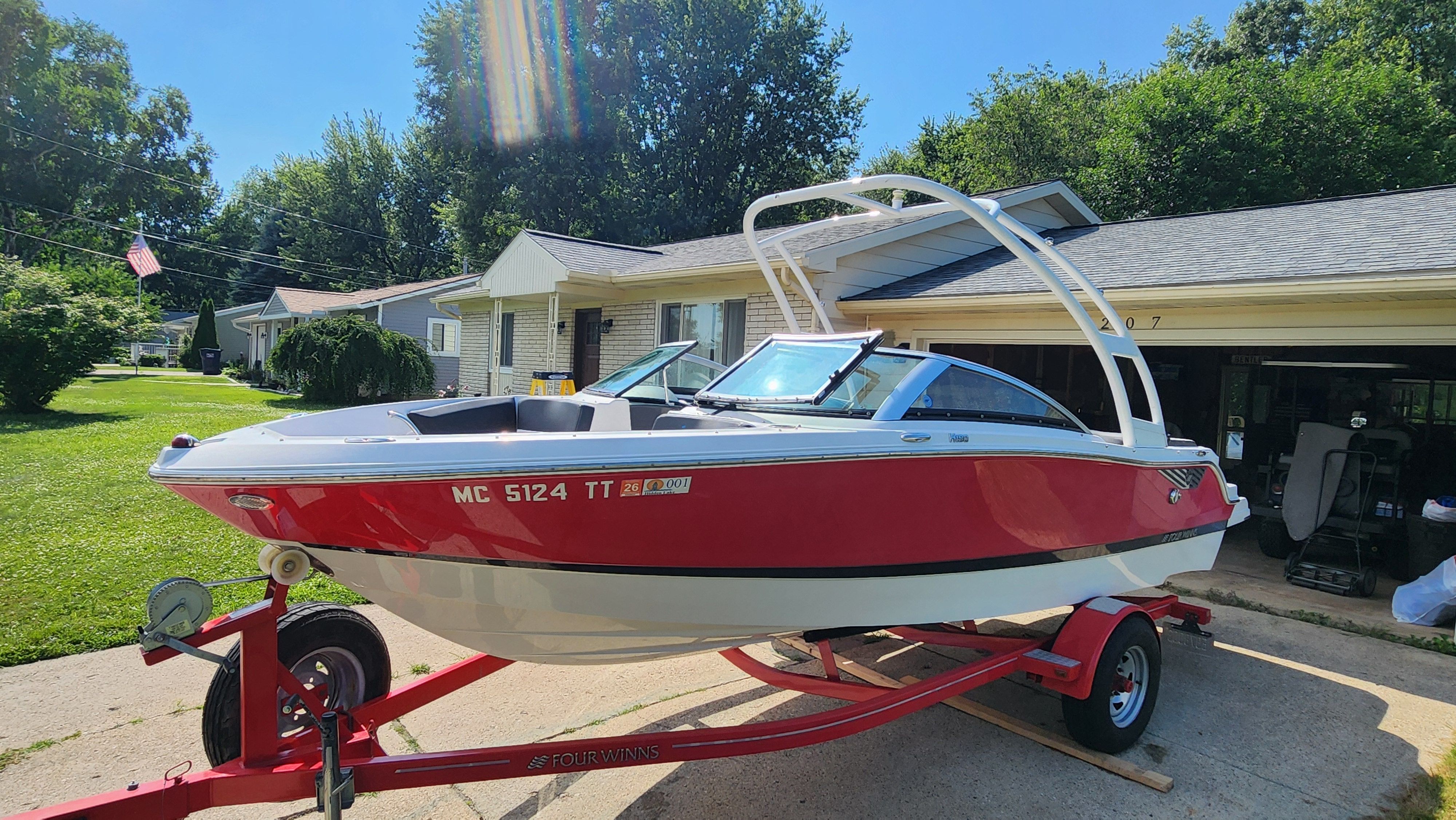 2015 Four Winns H190 boat on a trailer in front of a house.
