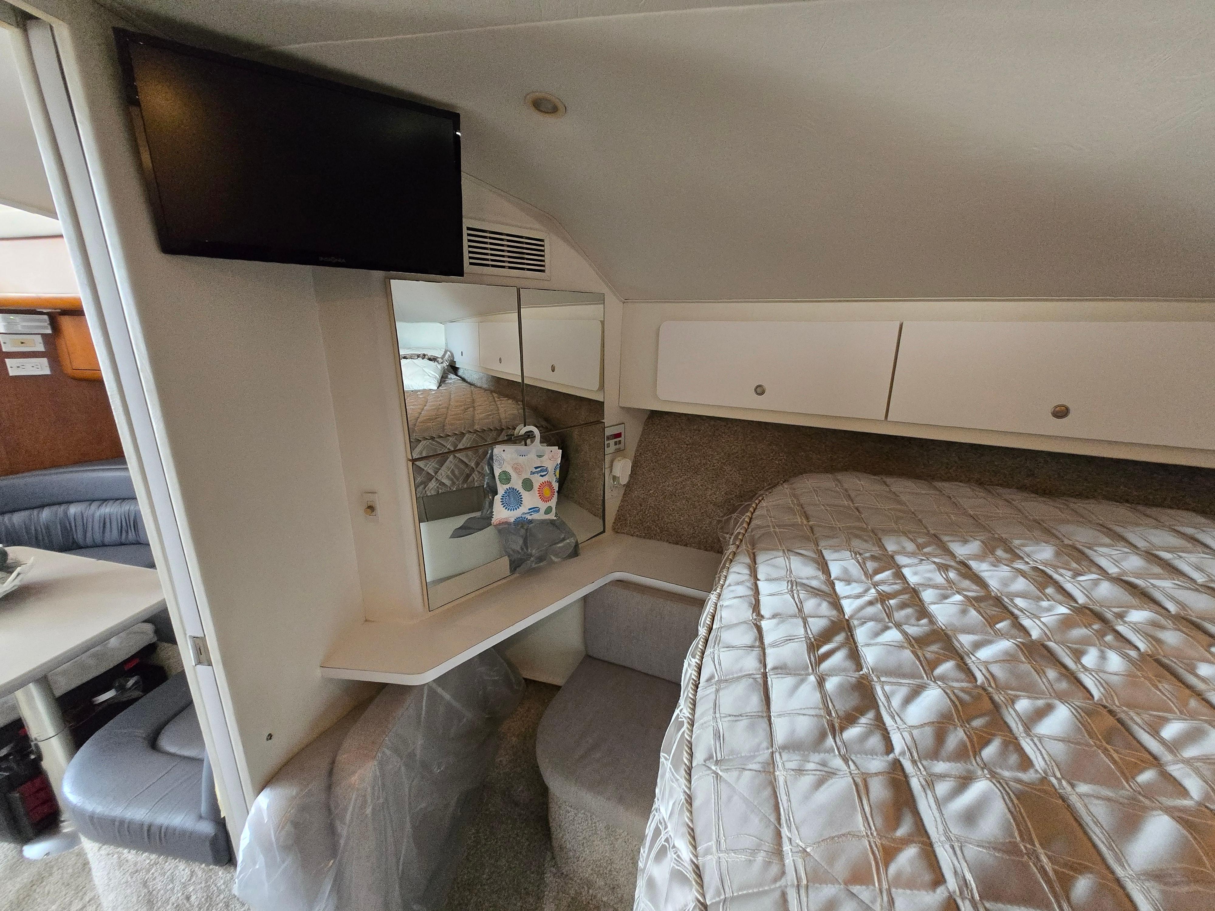 1996 Silverton 37 Convertible cabin interior with bed, TV, and storage cabinets.