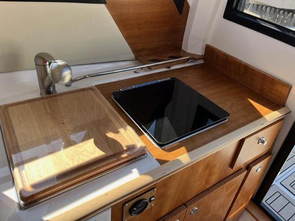 2025 Cutwater C-248 C Coupe boat kitchen with wooden cabinetry and modern appliances.