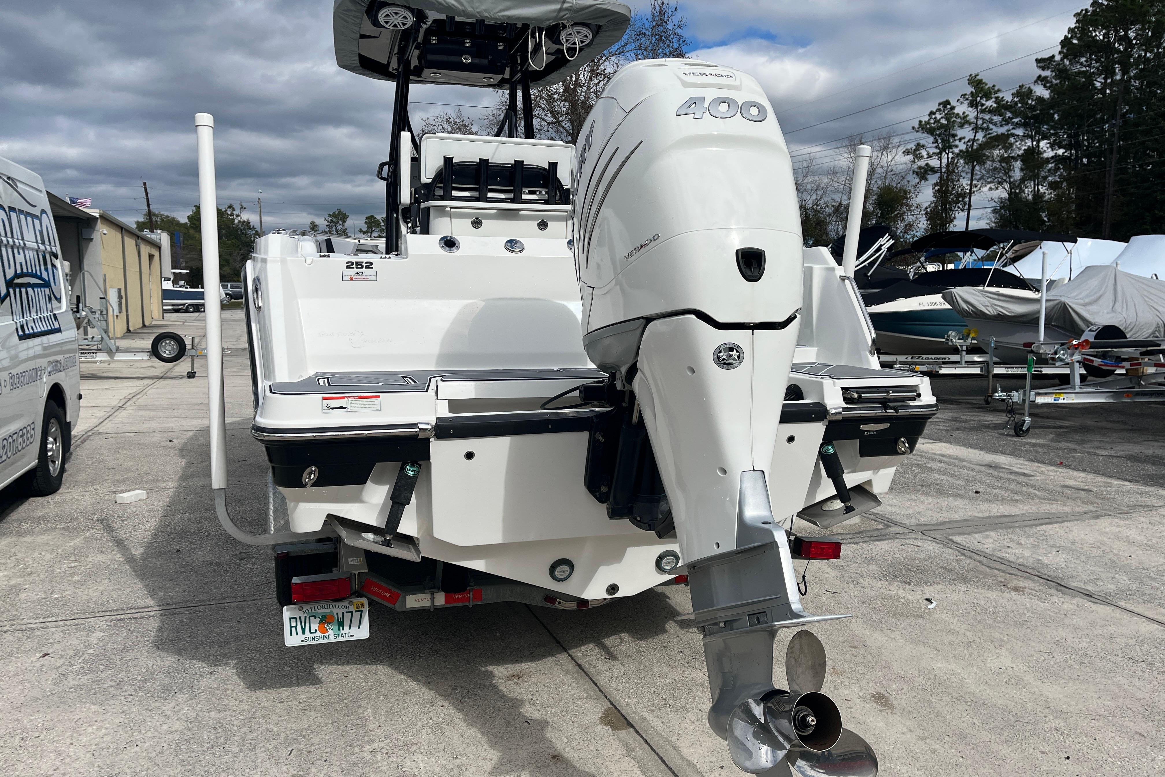 2021 Blackfin 252 CC boat with powerful outboard motor, parked on concrete lot.