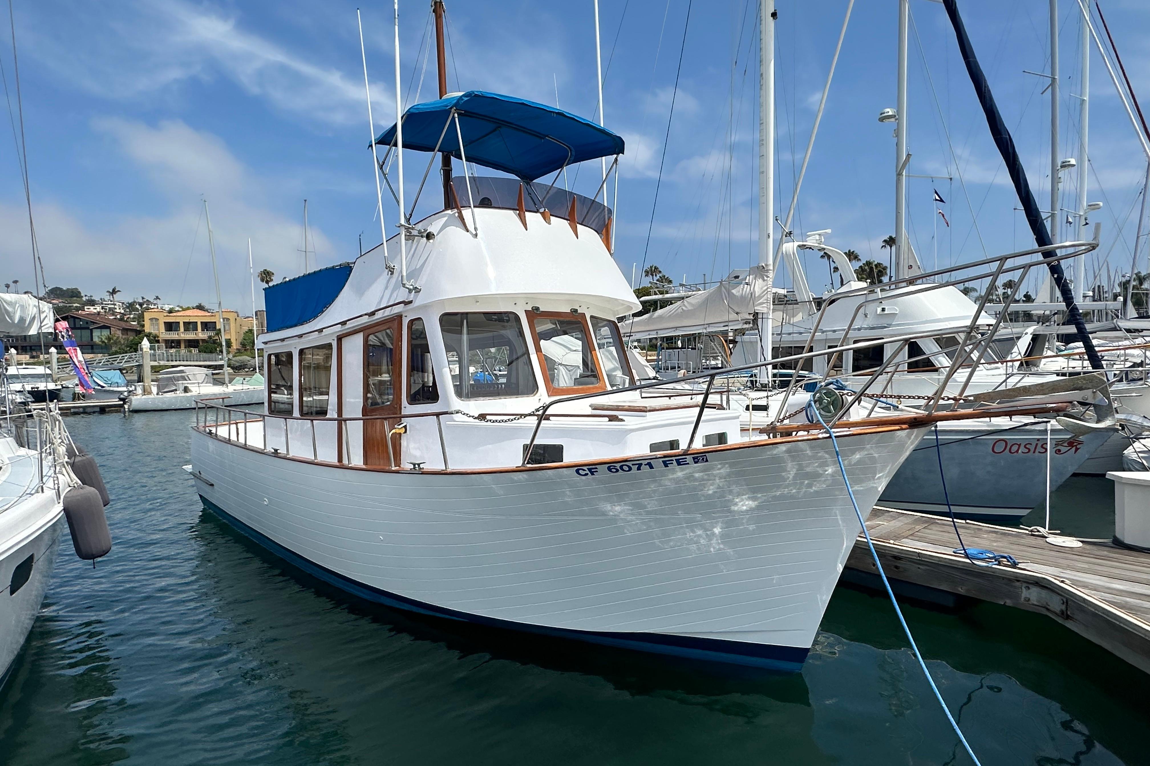 1973 CHB 33 boat docked in marina, featuring classic design and blue canopy.