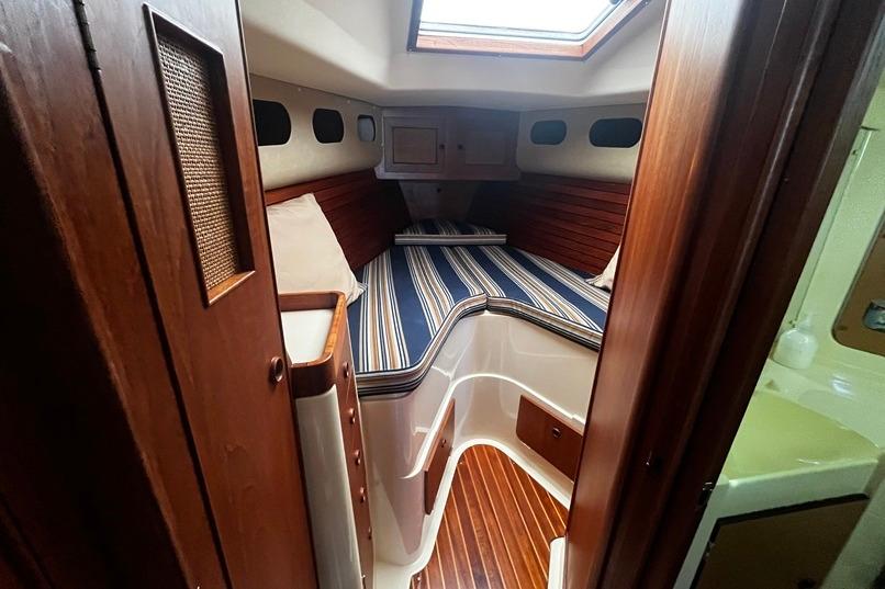 Interior of a 1980 CS 36 Traditional sailboat with striped bedding and wooden accents.