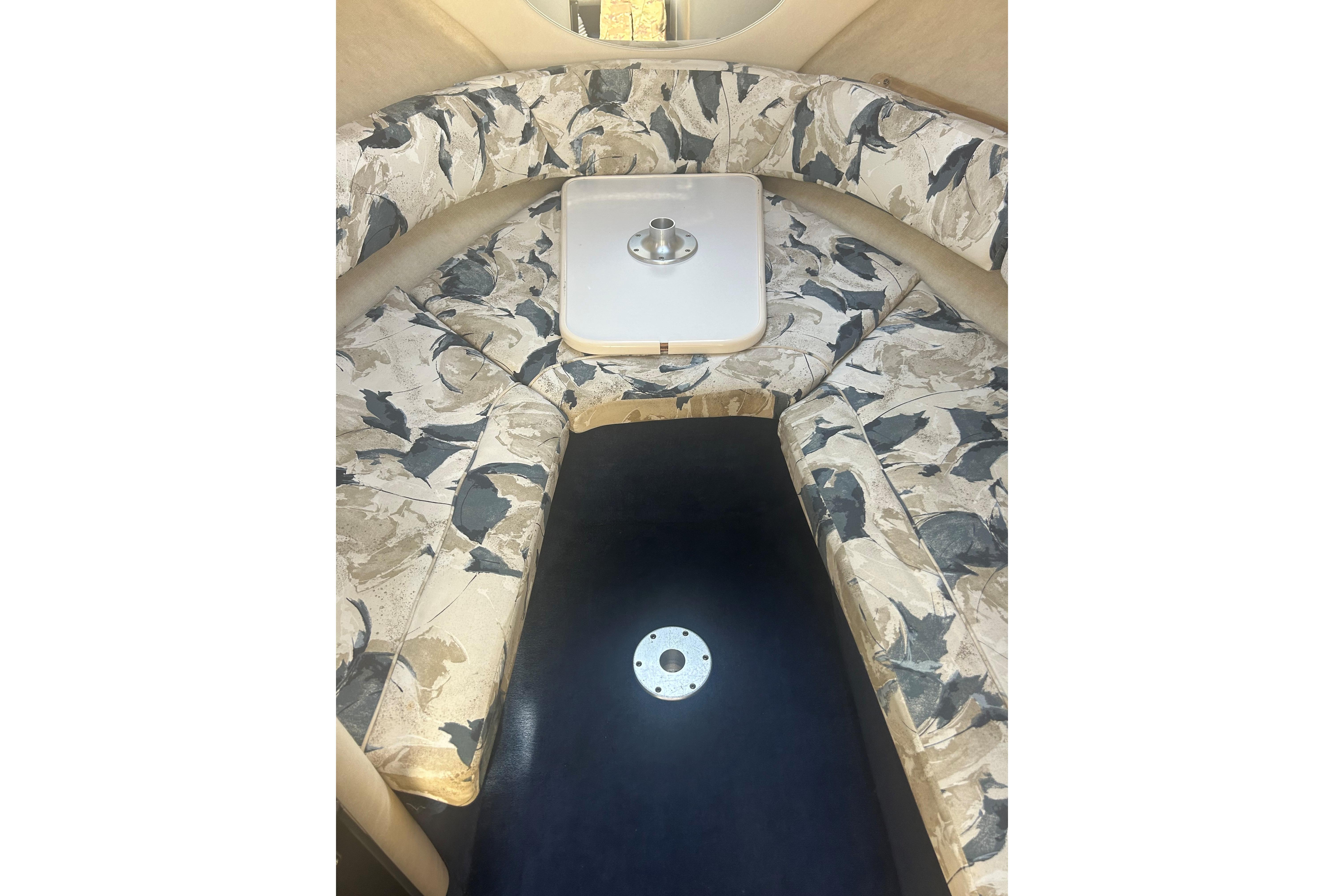 Interior of a 2000 Sea Ray 240 Sundancer with patterned seating and a central table.