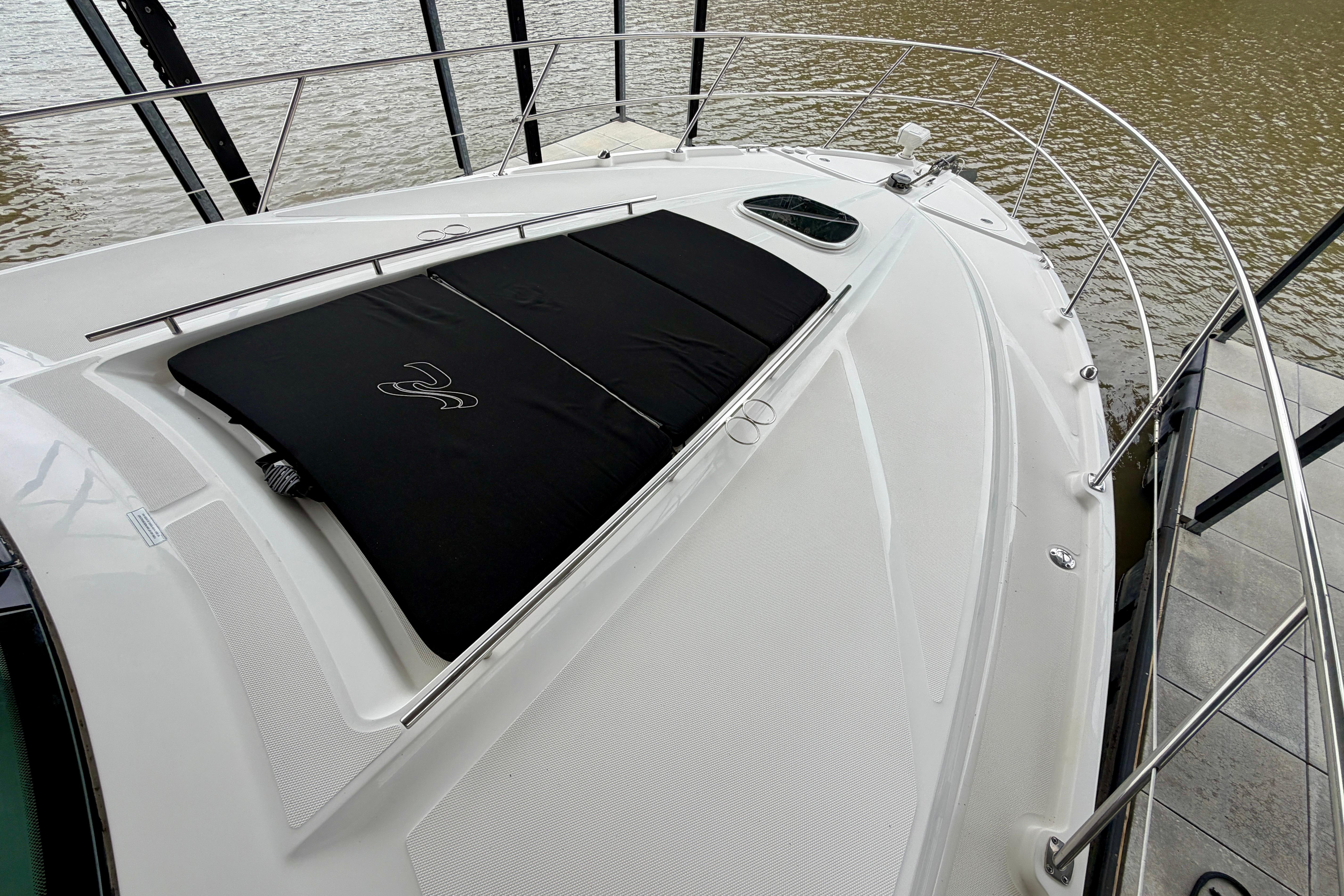 2012 Sea Ray 450 Sundancer yacht deck with black sunpad, docked by the water.