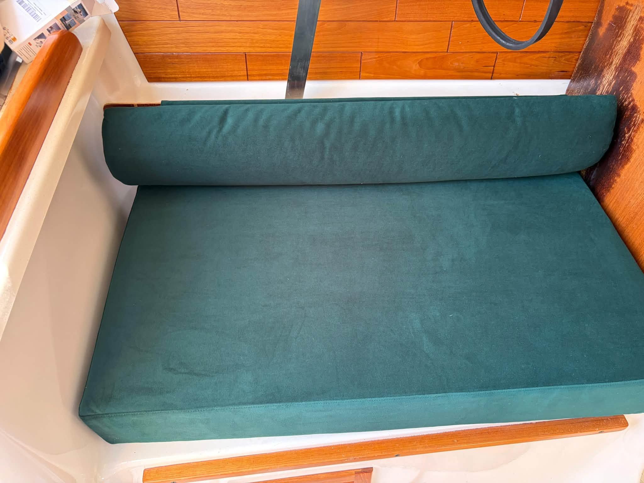 Green cushioned bench in a boat with wood paneling.