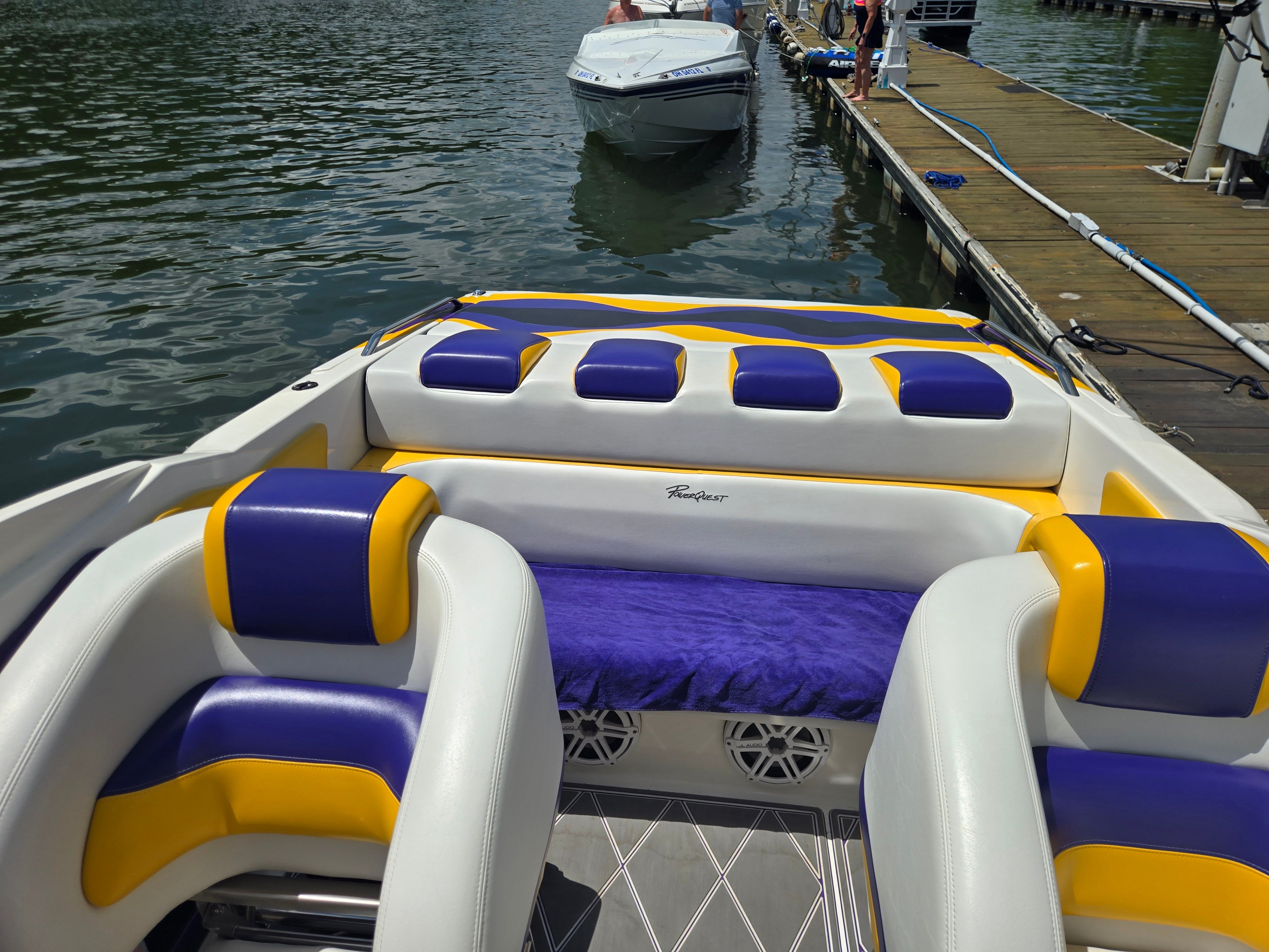 A boat with purple and yellow seats is docked on the water.