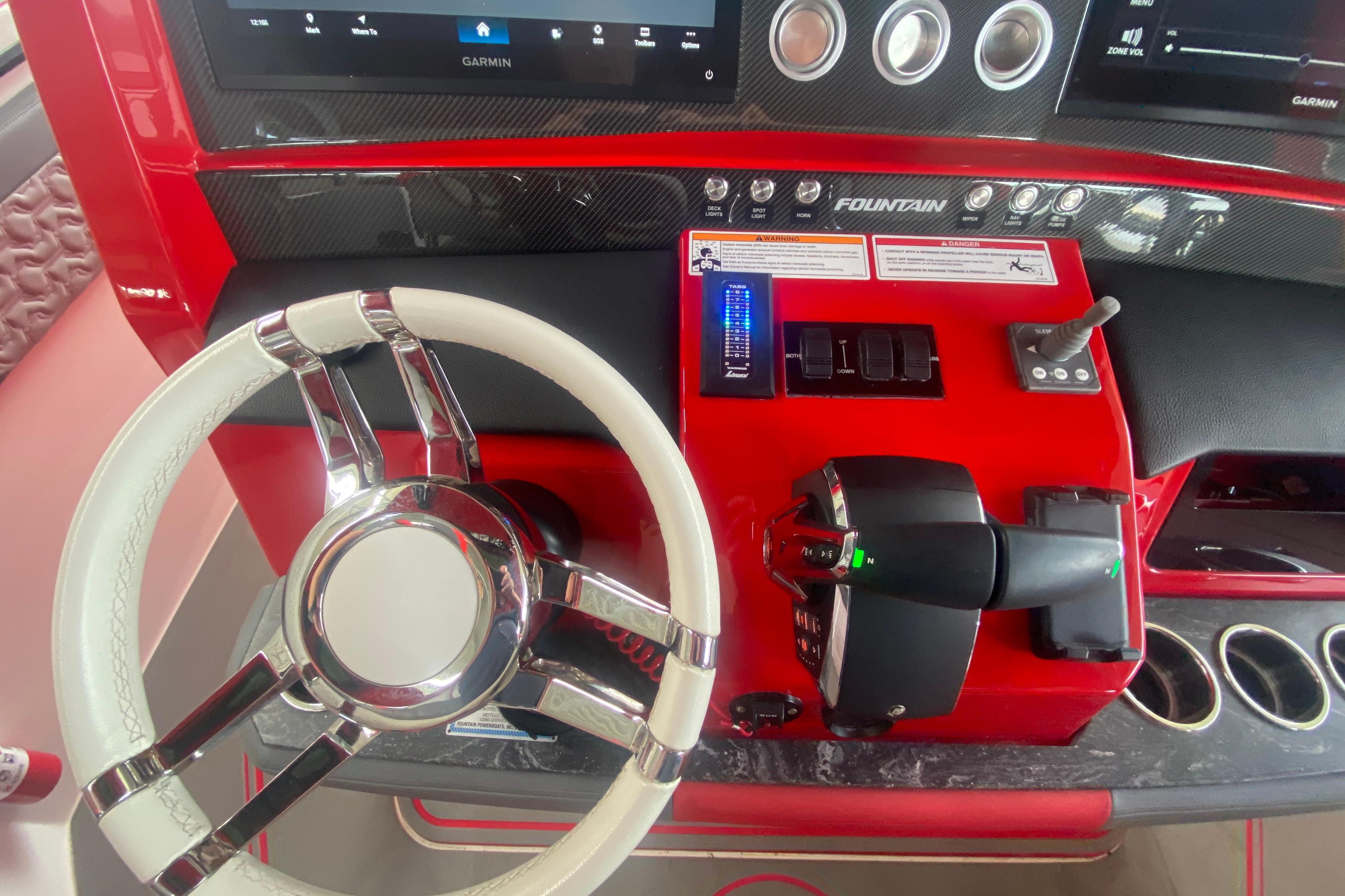Red and black dashboard of 2025 Fountain 38 SCX boat with steering wheel and controls.