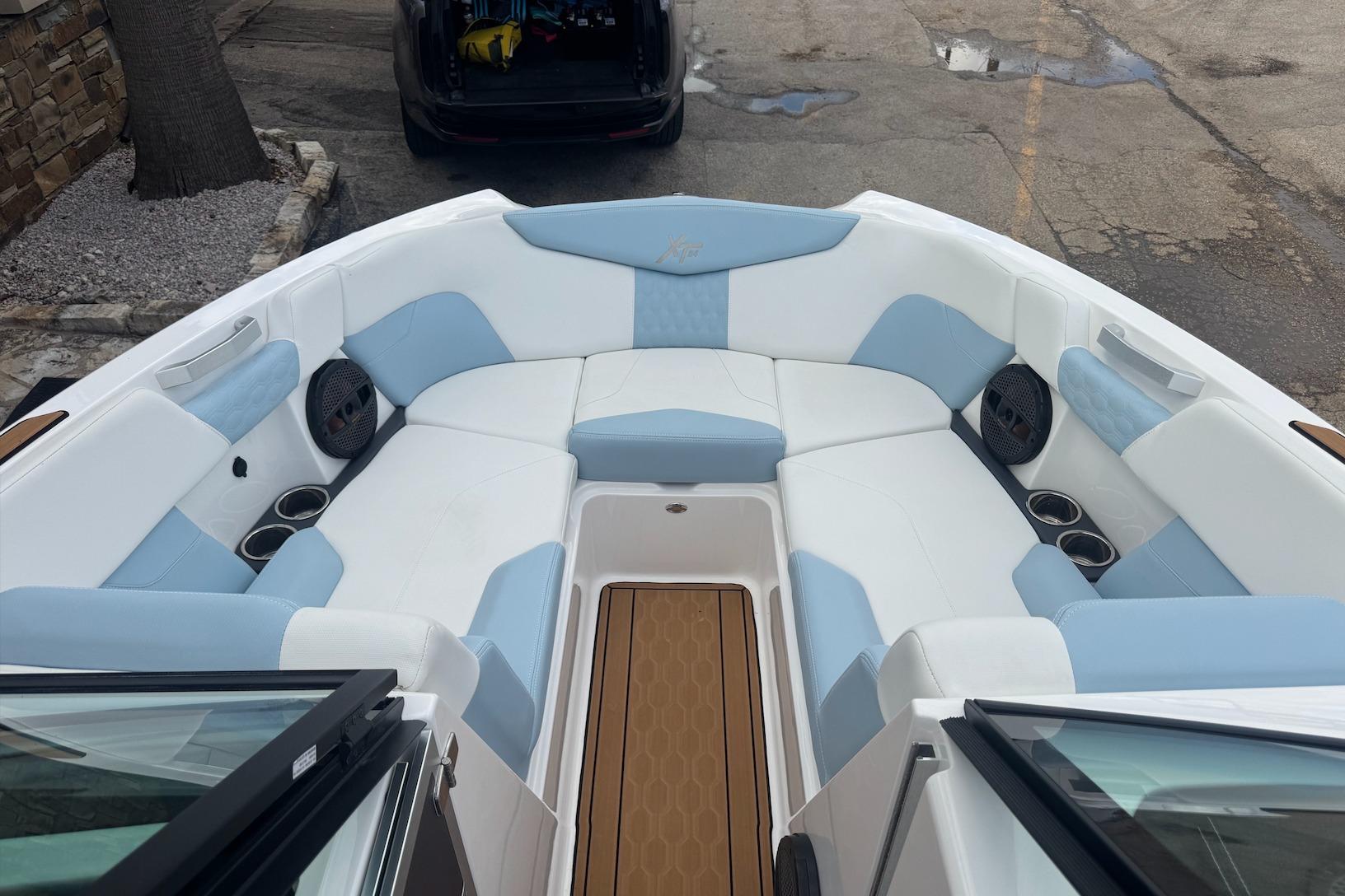 2023 MasterCraft XT24 boat interior with white and blue seating, cup holders, and speakers.